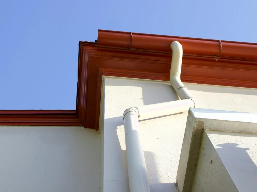 Roof gutter and downpipe on a rendered wall
