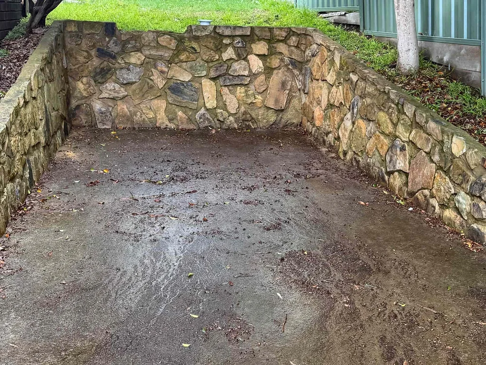 Concrete area between sandstone walls with mud and leaf staining before cleaning (Canberra)