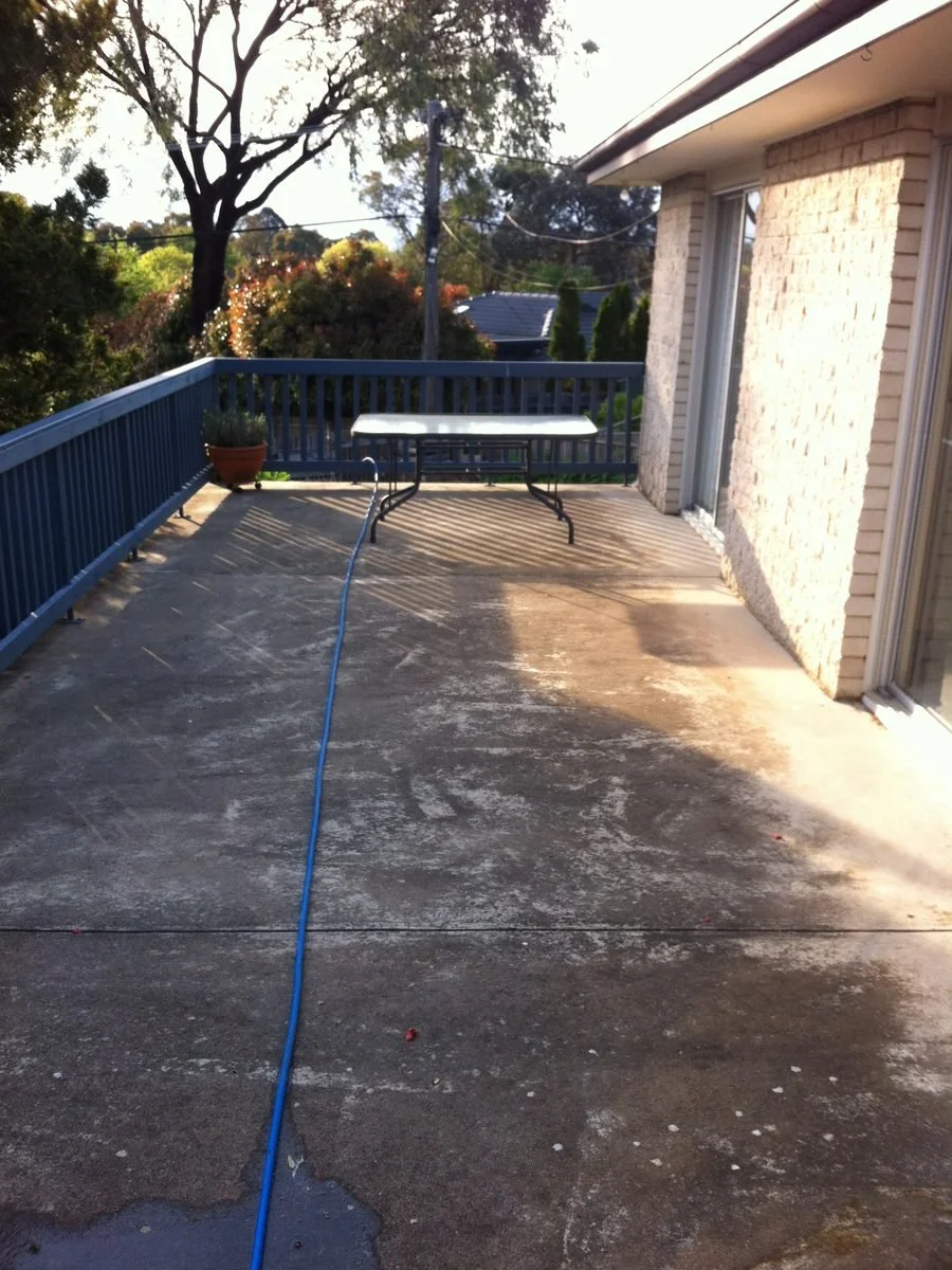 Concrete patio with dark growth and staining before cleaning (Canberra)