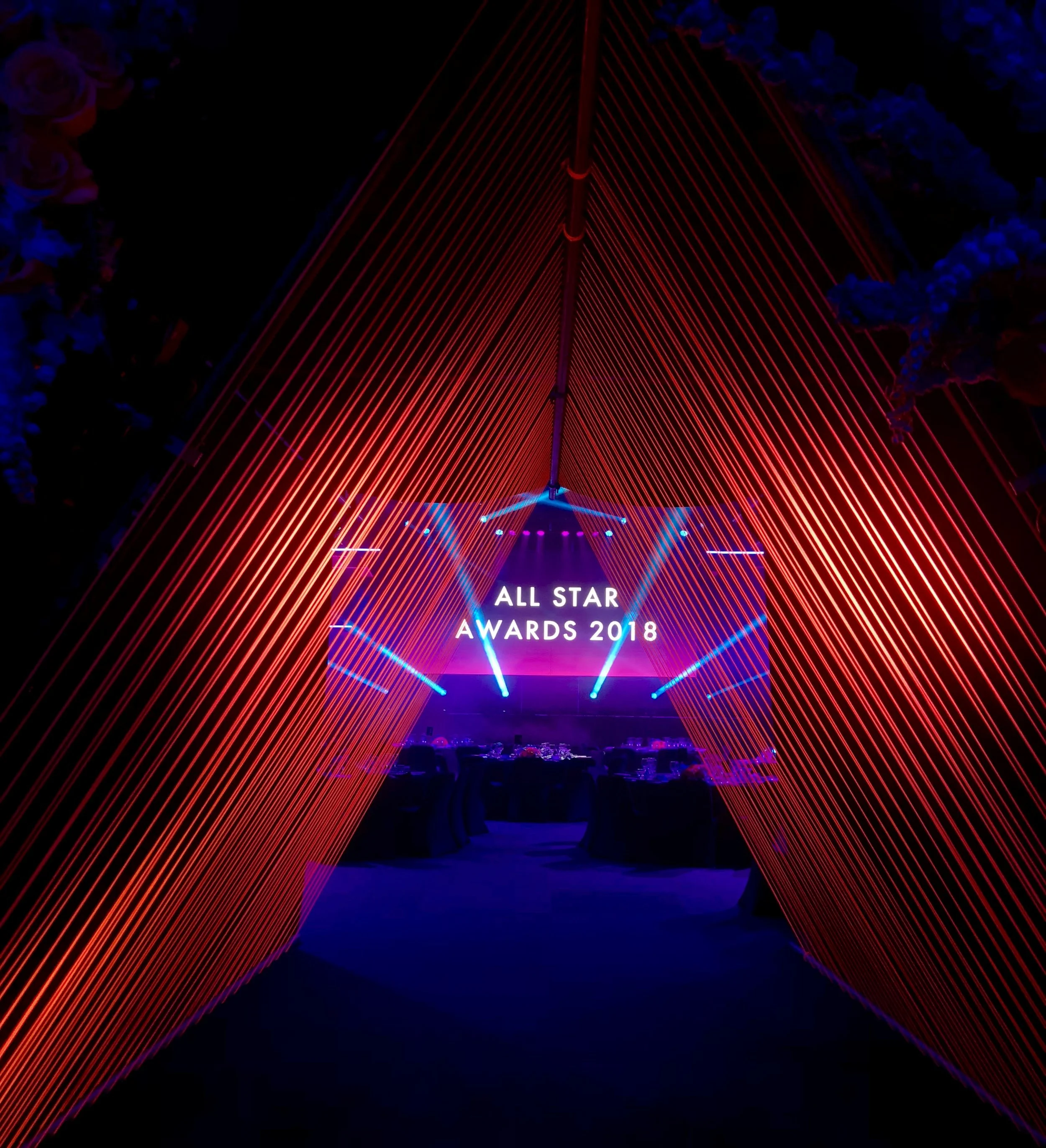 Our custom built entrance tunnel was a hidden behind a kabuki drop and was revealed to open the gala dinner. Four meters of high of local fresh flowers dispersed with hand cut and painted ultra saturate blue triangles decorated the front. Hundreds of feet of high reflect pink rope formed a another four meters long of tunnel.