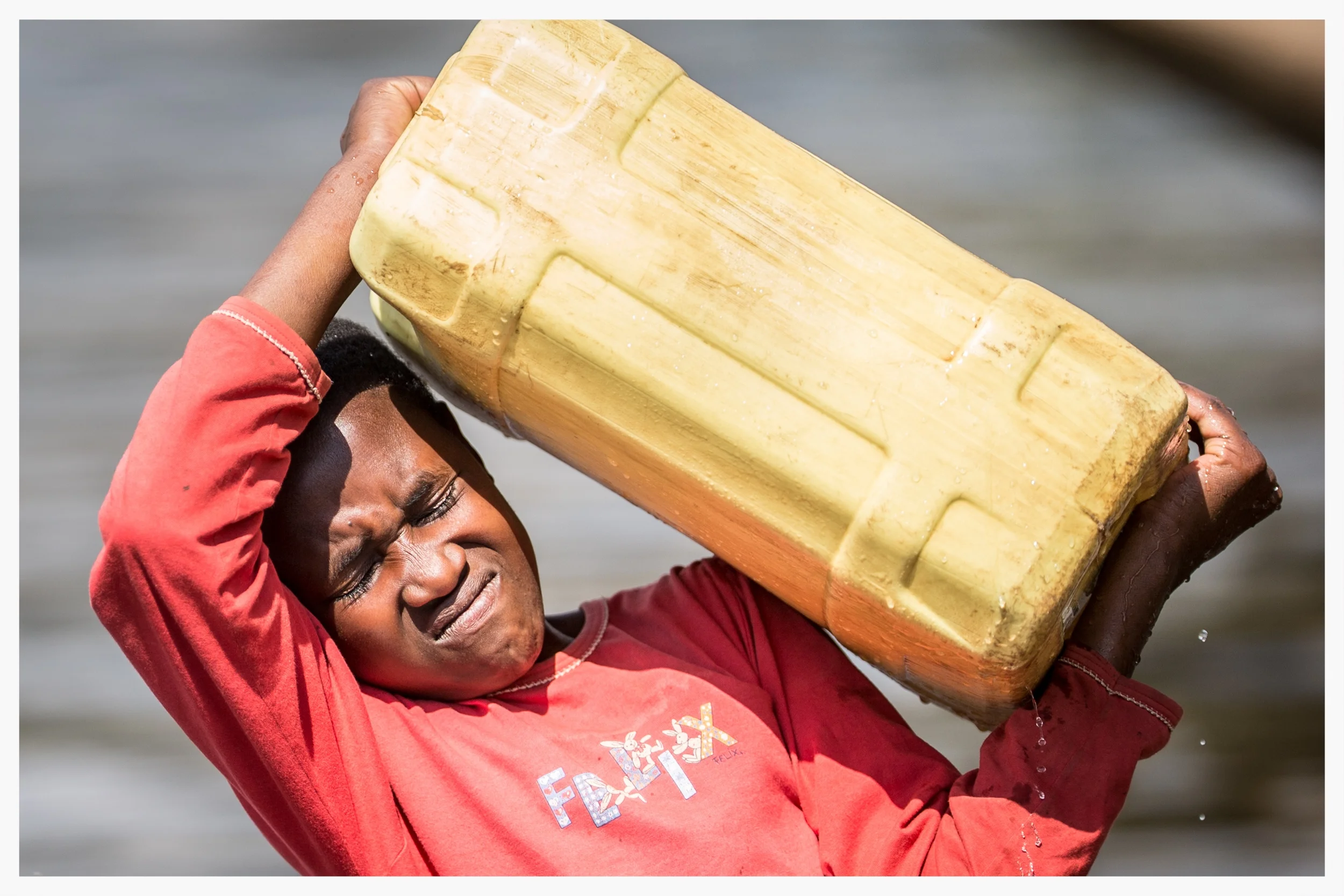 Lifting 20 litres of water (20kg) is tough for an 11-year-old girl. Photo © Marcus Perkins