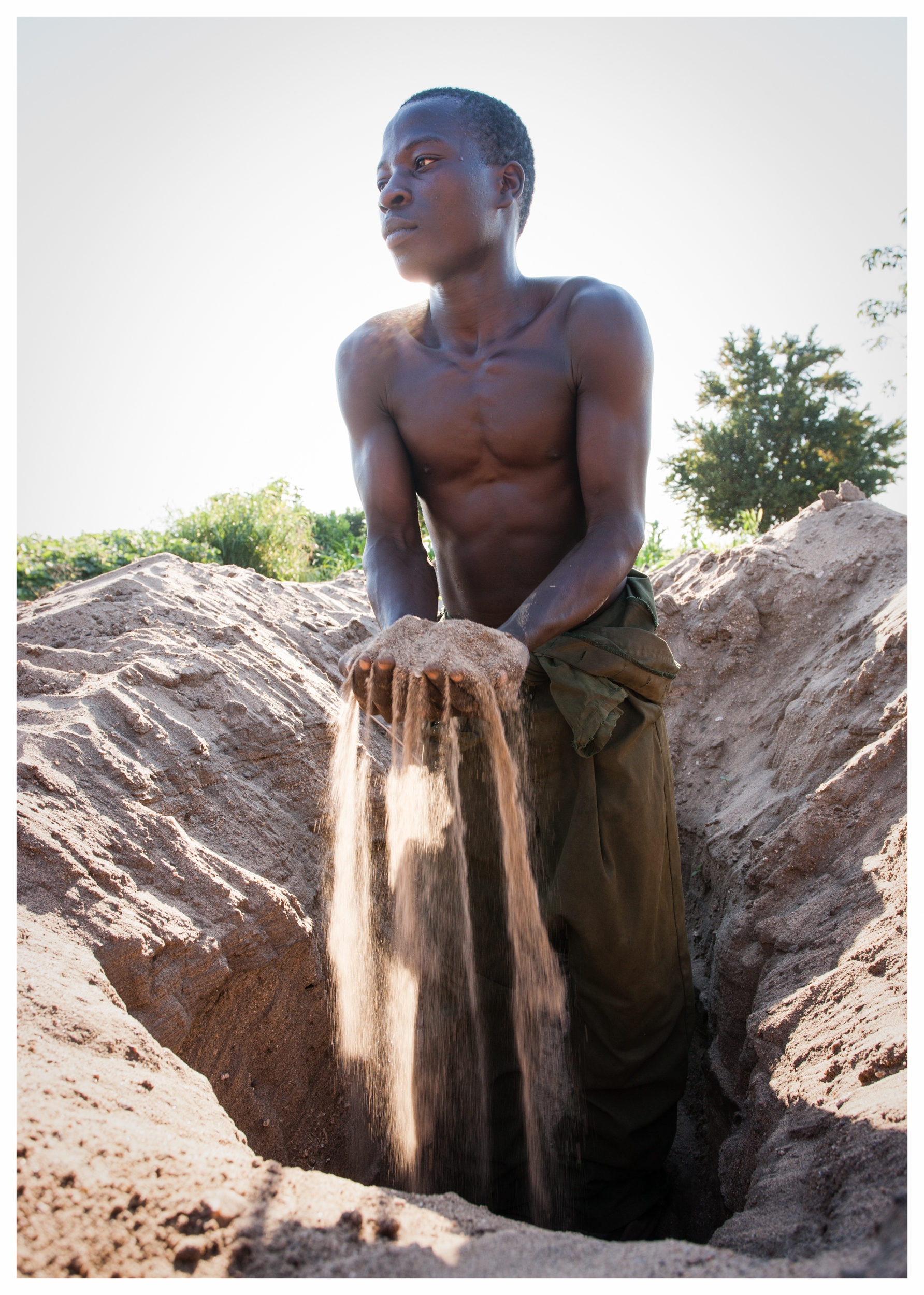 Andrew digs through sand to find fertile soil for his crop. Fombe, Chikwawa, Malawi. Photo © Marcus Perkins
