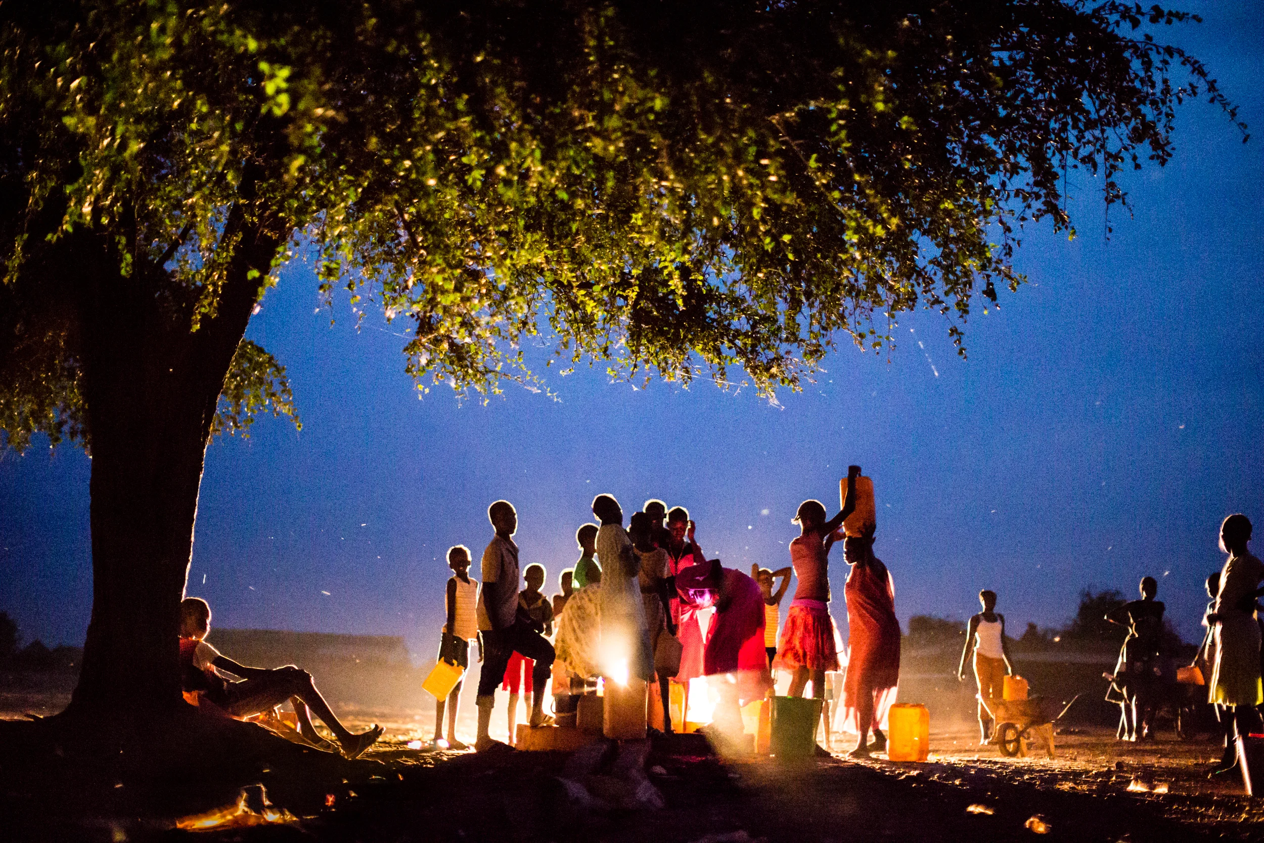 Children collect water at dusk in Kuajok. With few functioning boreholes in Warrap, pressure on the ones that work can be intense. When disagreements occur, they can escalate quickly and violence is not uncommon as families and communities step in to defend their side. Warrap State, South Sudan. From Saferworld's 25th anniversary exhibition Communities first , funded by the Kingdom of the Netherlands.