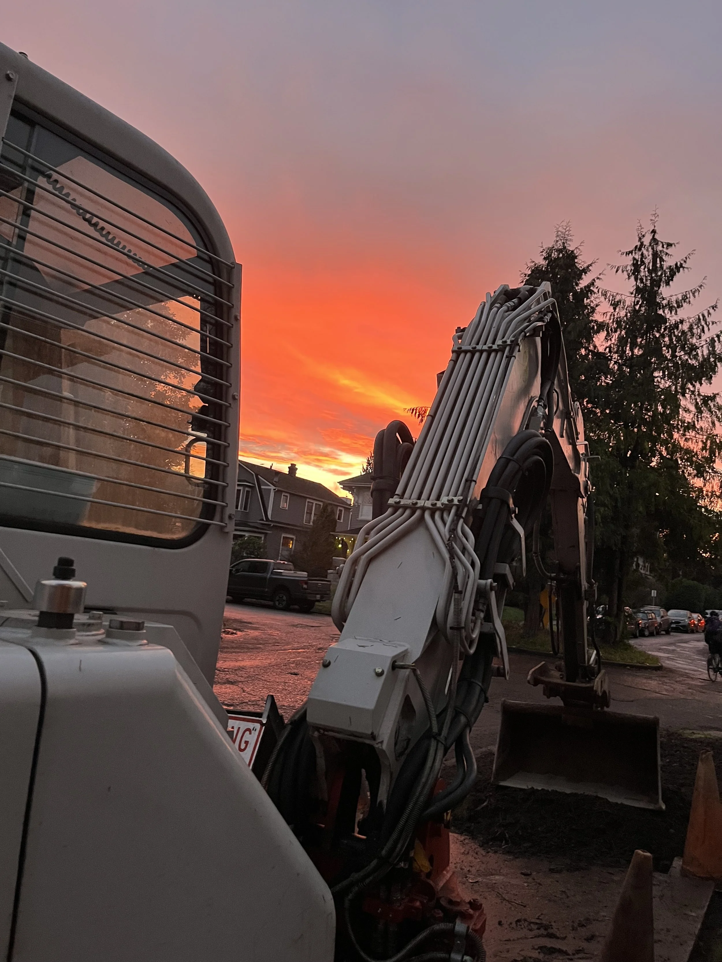 Construction excavator at sunset in a residential neighborhood.