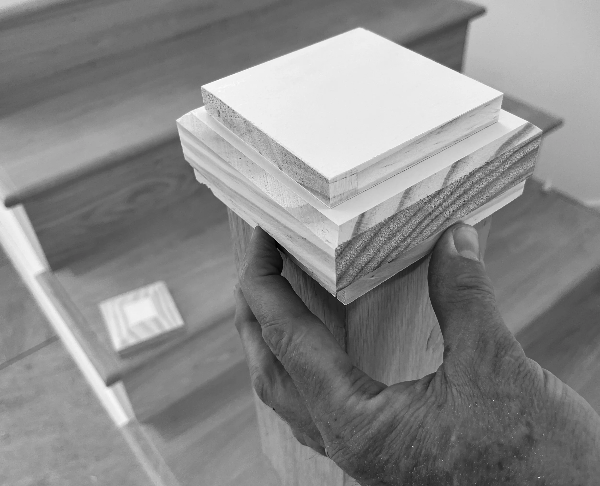A person holding a stack of various wooden and drywall samples in their hand.