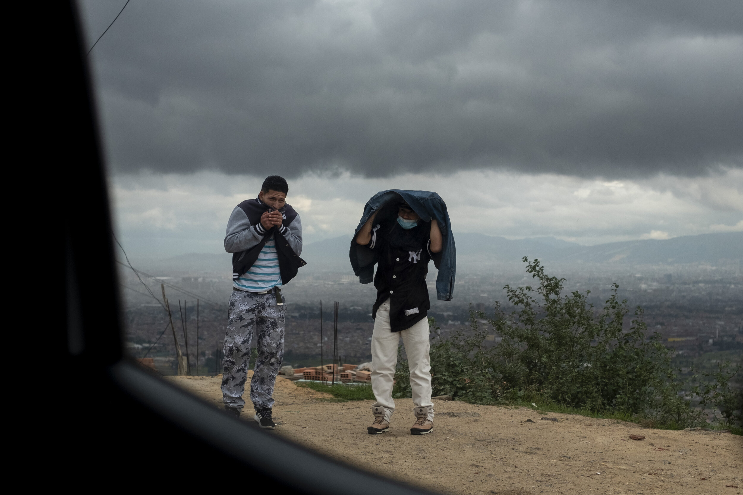  A pair of young man stand outside in the high altitude and chilly air of Ciudad Bolivar in Bogotá. 