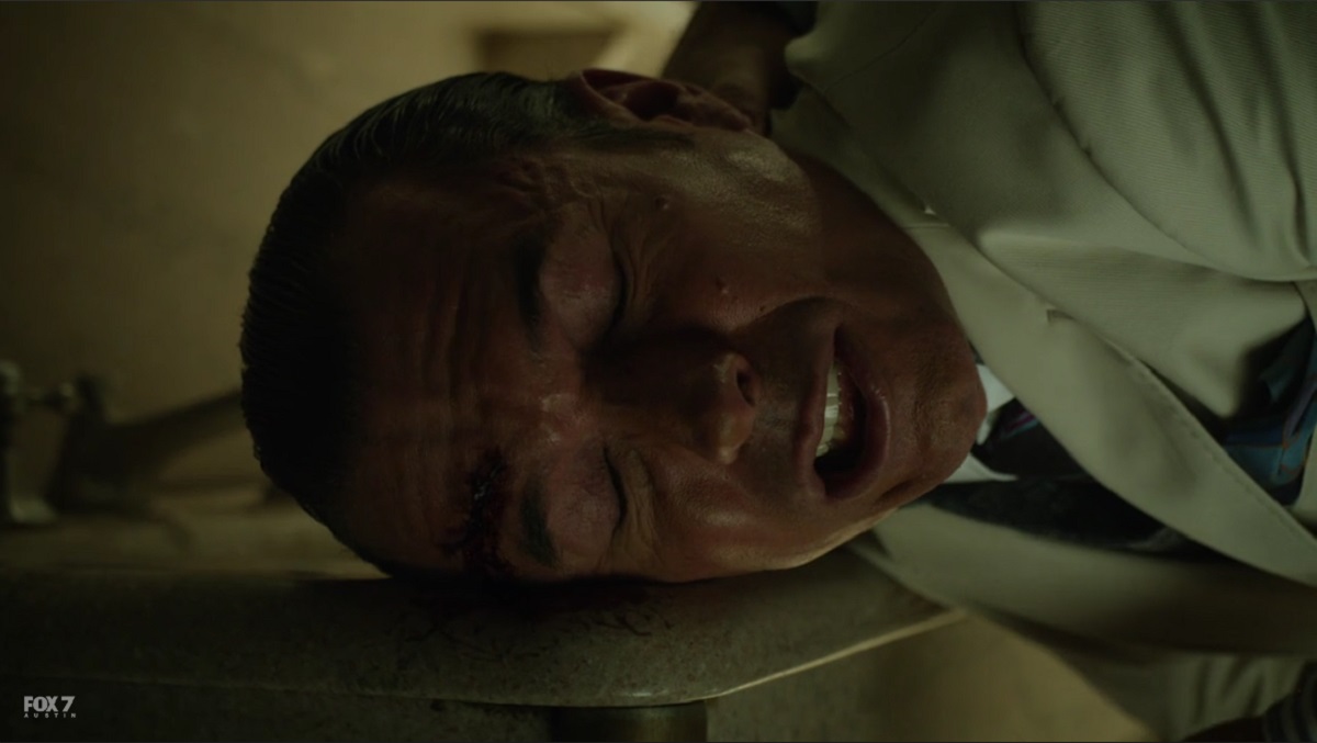 Barnes smashes Symon into the sink before throwing him through a bathroom stall.