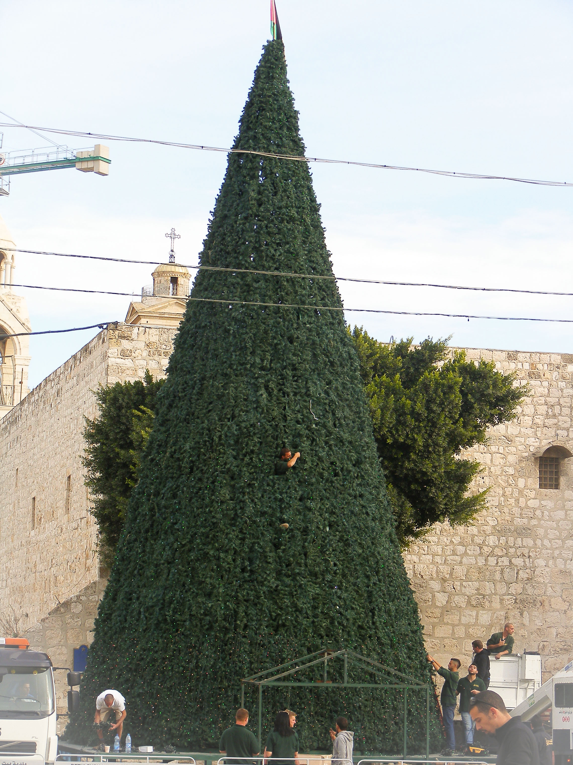 Preparation of the Christmas tree in Manger Square, Bethlehem. Church of the Nativity in the background. 
