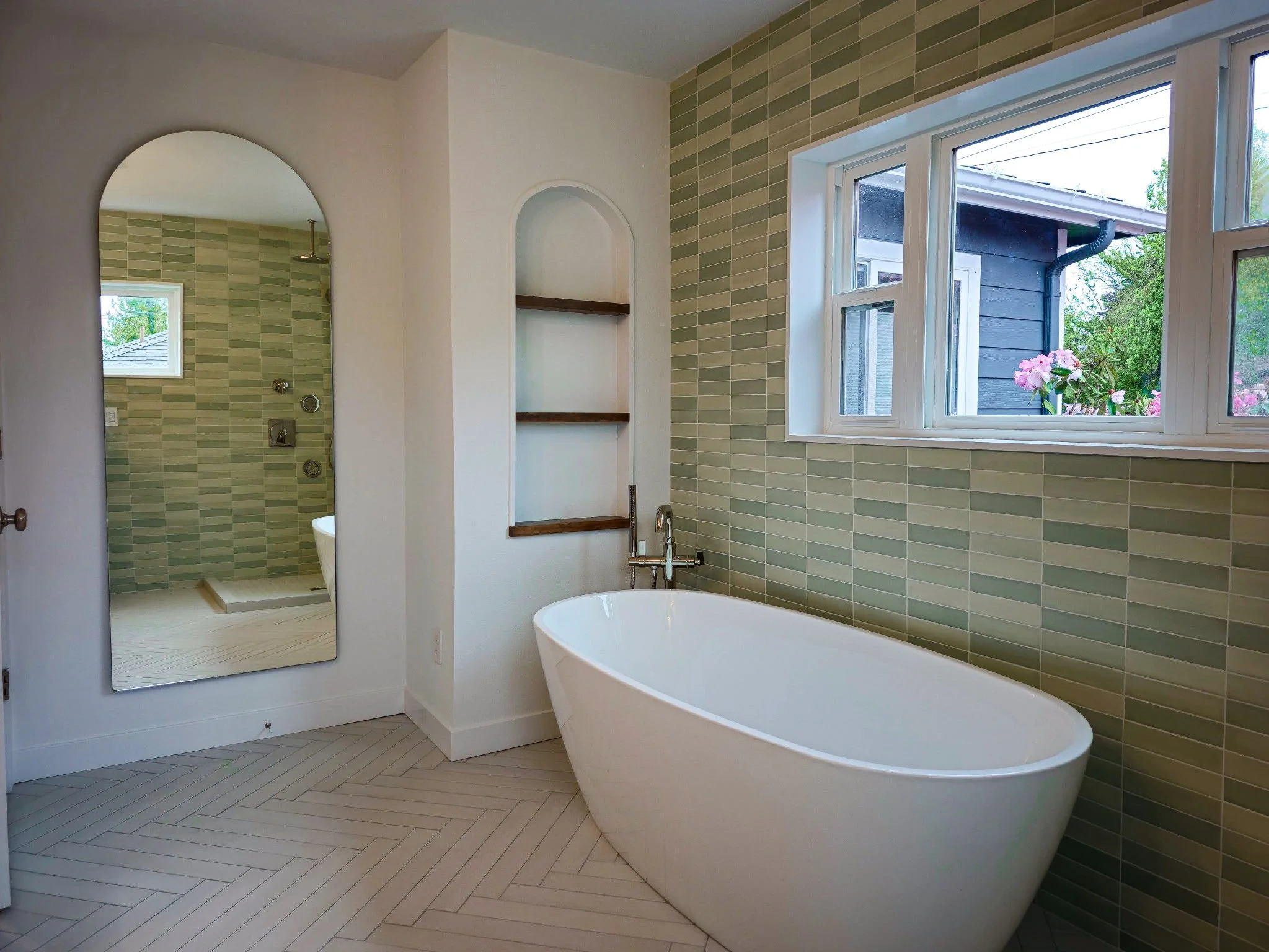 Full bathroom renovation with herringbone tile flooring, green subway tile walls, freestanding bathtub, and walk-in shower with custom niches in SW Portland, OR