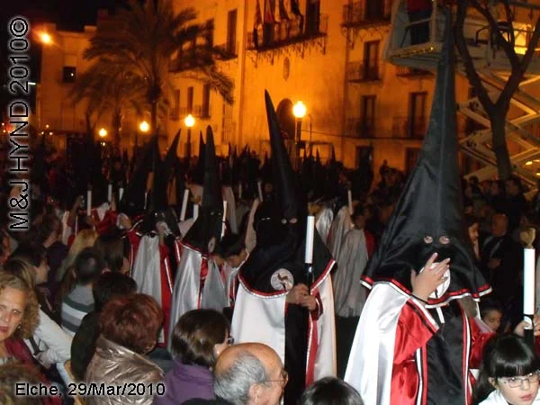 spain elche, Brotherhood long pointed hat hood, long capes carry candles, procession, at Elche Ayuntamiento, Townhall, crowded street parade