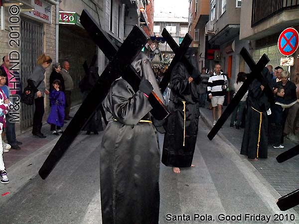  spain Santa Pola, Semana Santa Holy Week, Good Friday procession, Brotherhood hooded, long black capes Penitents, bare-footed, carry huge black cross, somber march, long pointed blue hood, uniforms 