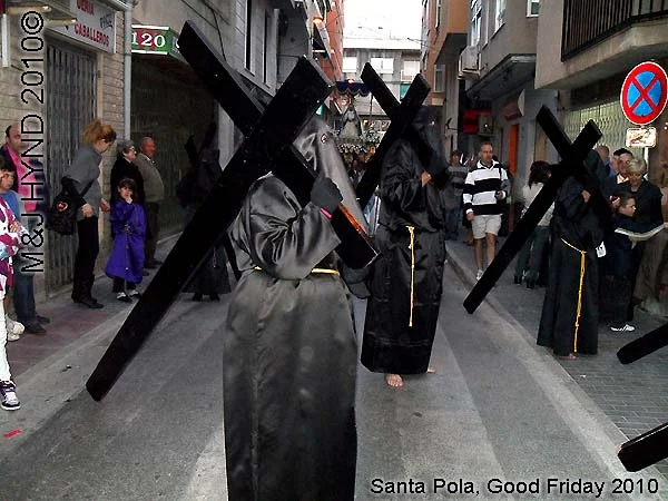 spain Santa Pola, Semana Santa Holy Week, Good Friday procession, Brotherhood hooded, long black capes Penitents, bare-footed, carry huge black cross, somber march, long pointed blue hood, uniforms