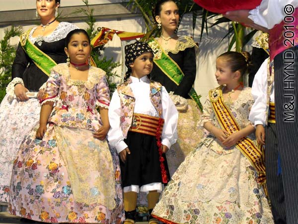 on stage 3 littlies, 2 teenagers: spain perleta maitino St Vicente de Ferrer Fiesta, kings queens ladies-in-waiting, traditional long ballgowns, boys tuxedo, winner's sashes, stage