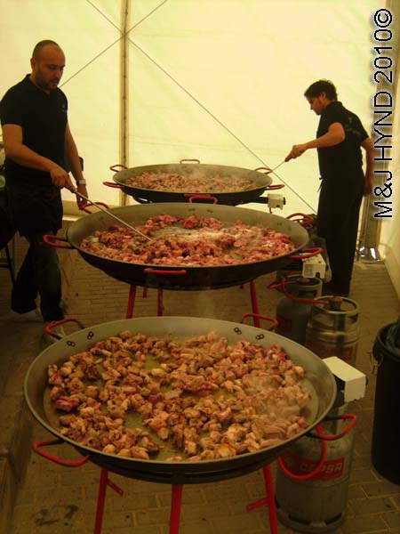 paella cooking: spain perleta maitino St Vicente de Ferrer Fiesta, giant paella, searing the meat - sausages chorizos, Arroz con Costra