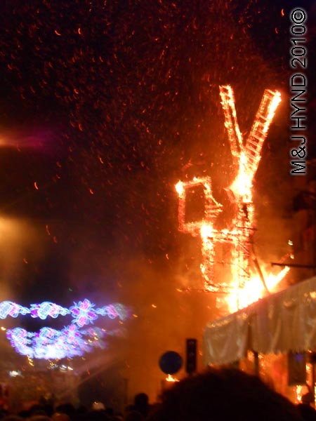 burning hoguers looks like windmill: spain Alicante Fiesta Hogueras de San Juan Bonfires of Saint John, firehoses douse burning, up in flames, International Tourist Interest, celebrate summer solstice