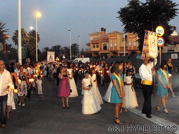 sombre parade: spain valverde fiesta La Virgen de Santa Ana, candle-lit procession, traditional baptism dressed in white, flag-bearers