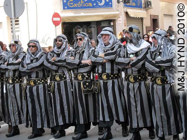 grey+black striped: spain Santa Pola Annual Fiesta, Moorish men, costumed grey+black striped arm-in-arm procession