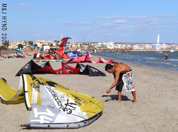 Spain Santa Pola, kite-surfers getting their stuff ready, town in background