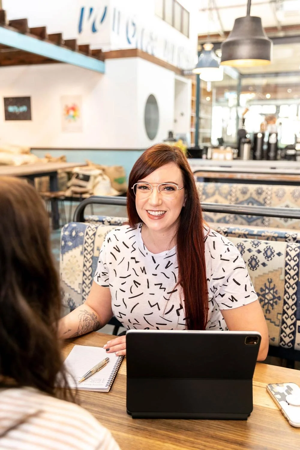 Perth branding & logo designer, Joanne Tapodi with her iPad in a design meeting with a client in a cafe.