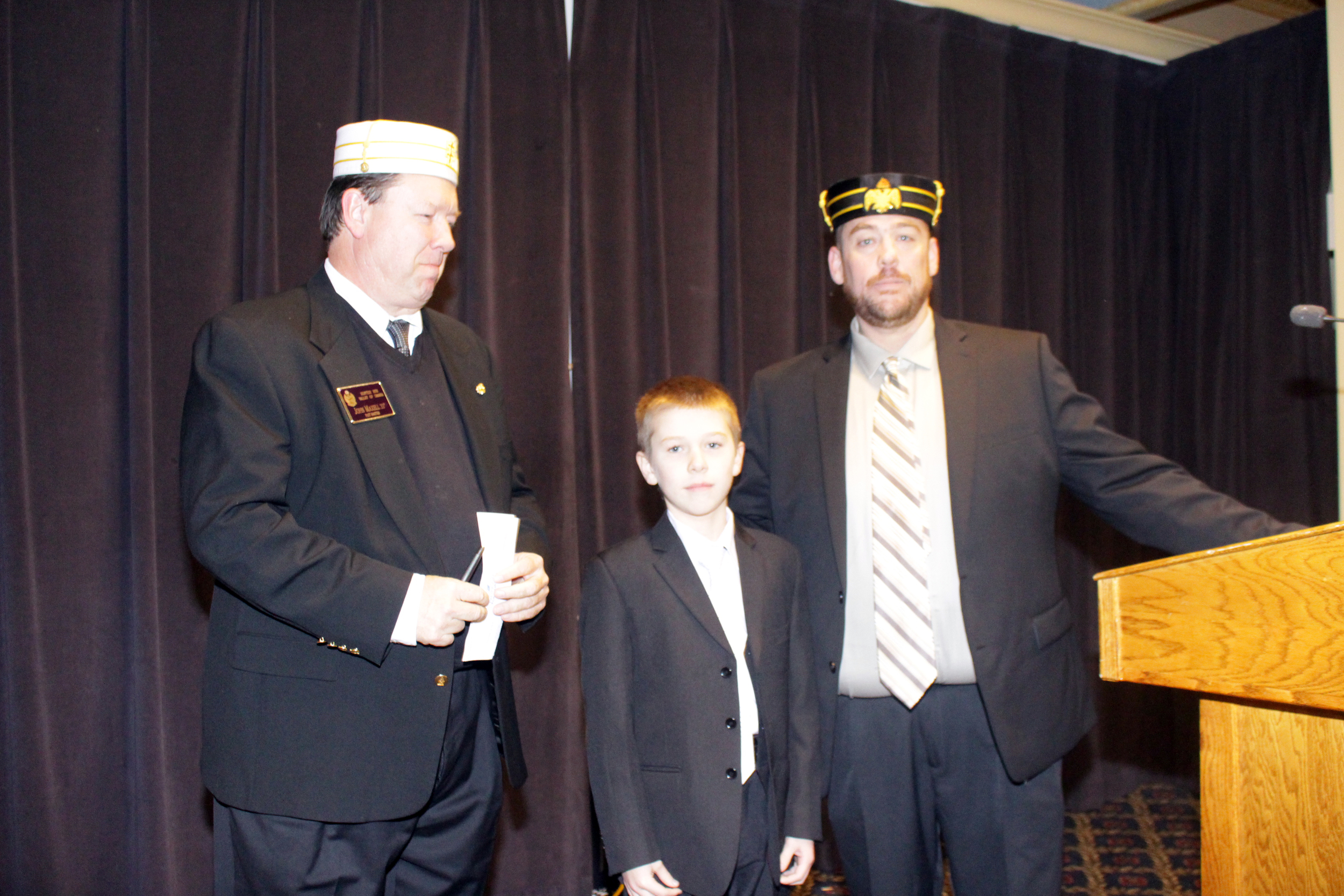 Mike O'Donnell, 32°, assisted by son Kody, presents a check for $5,000 to John Maxell, 33°, at the November 16 Lodge dinner.