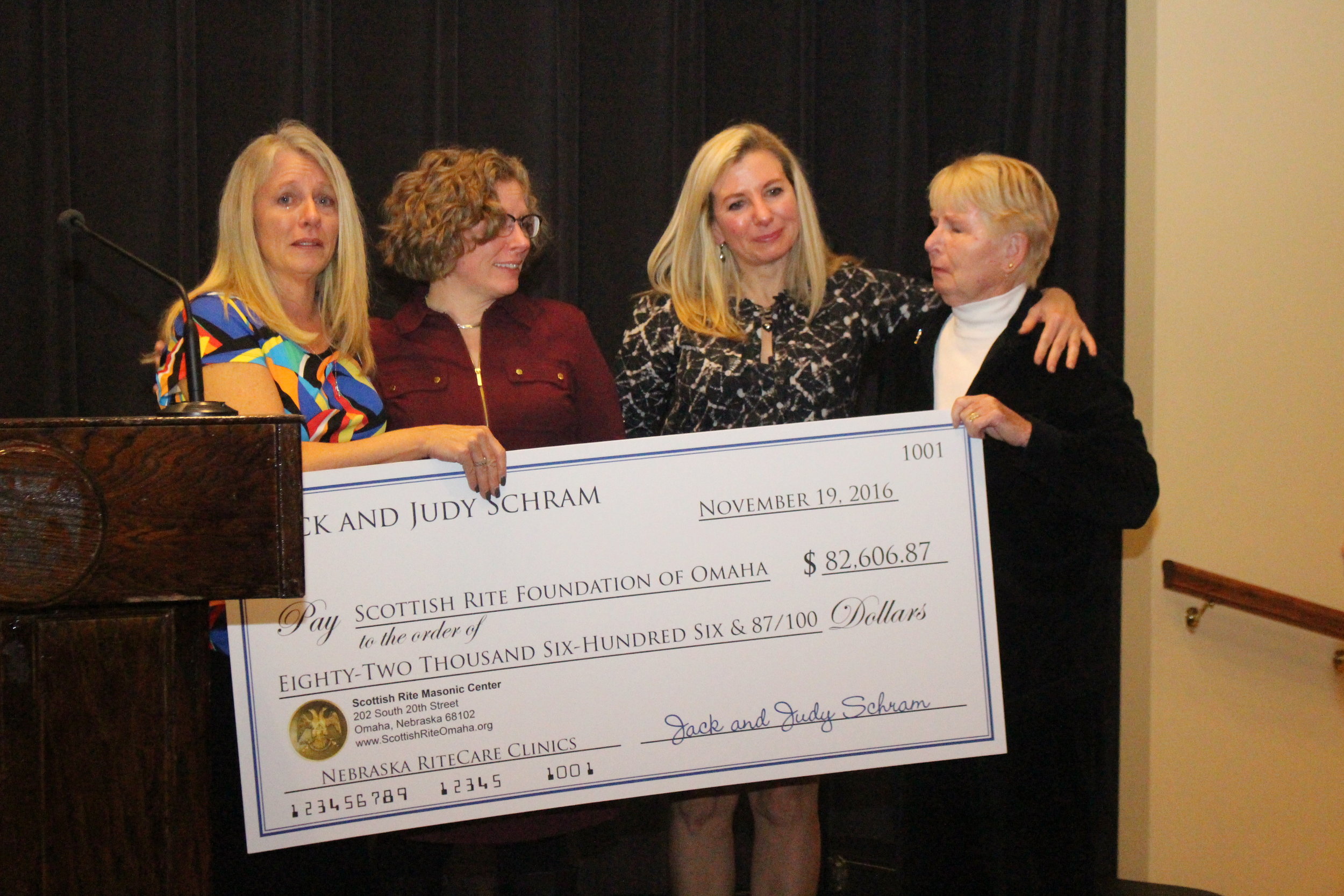 Judy Schram and daughters presenting a check to the Omaha Foundation for RiteCare at the Reunion Banquet Saturday evening.