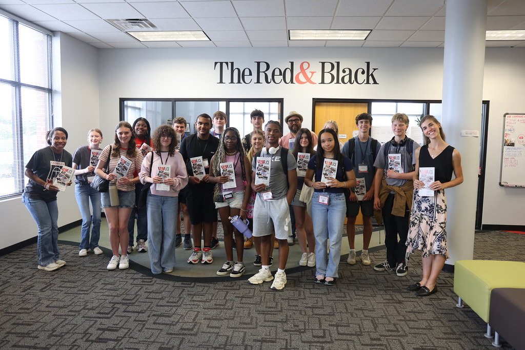 Students pose for a photo at a local newspaper holding a publication.