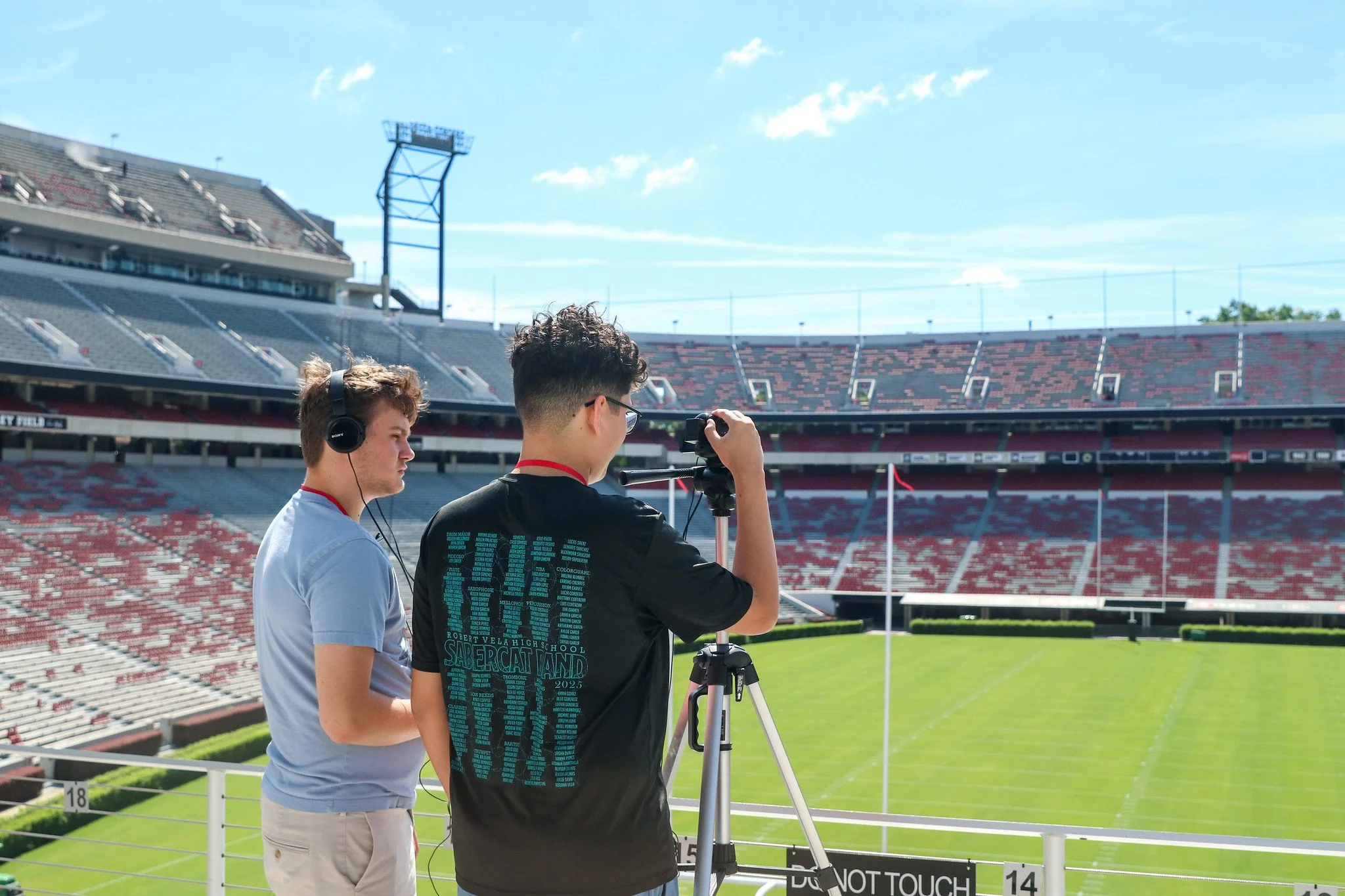 Two students operate a camera overlooking a large collegiate football stadium