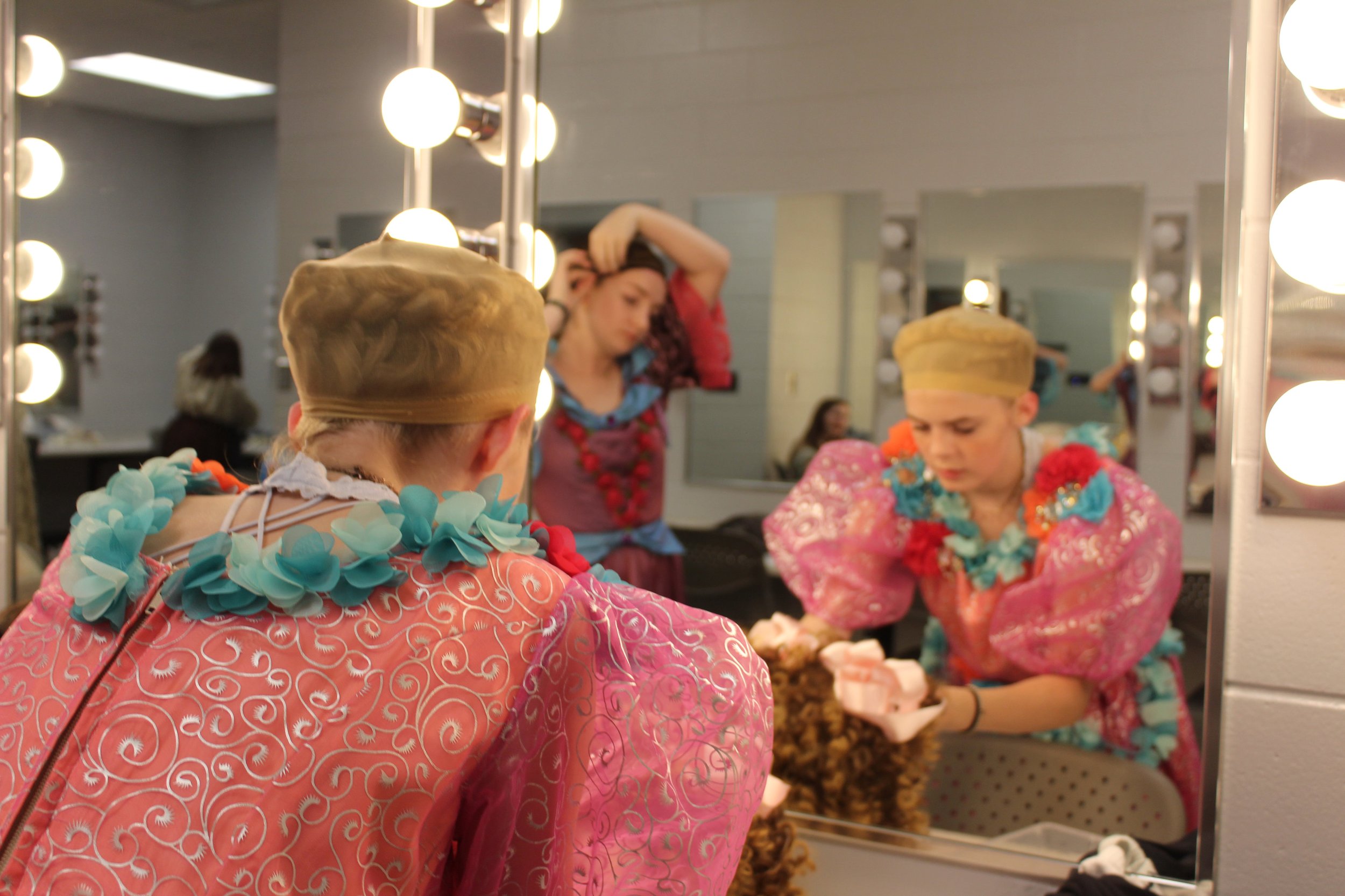  Elizabeth Mullis (12) gets ready to put her wig on for dress rehearsal. She plays one of Cinderella’s evil stepsisters in the “Into the Woods” one-act play. 