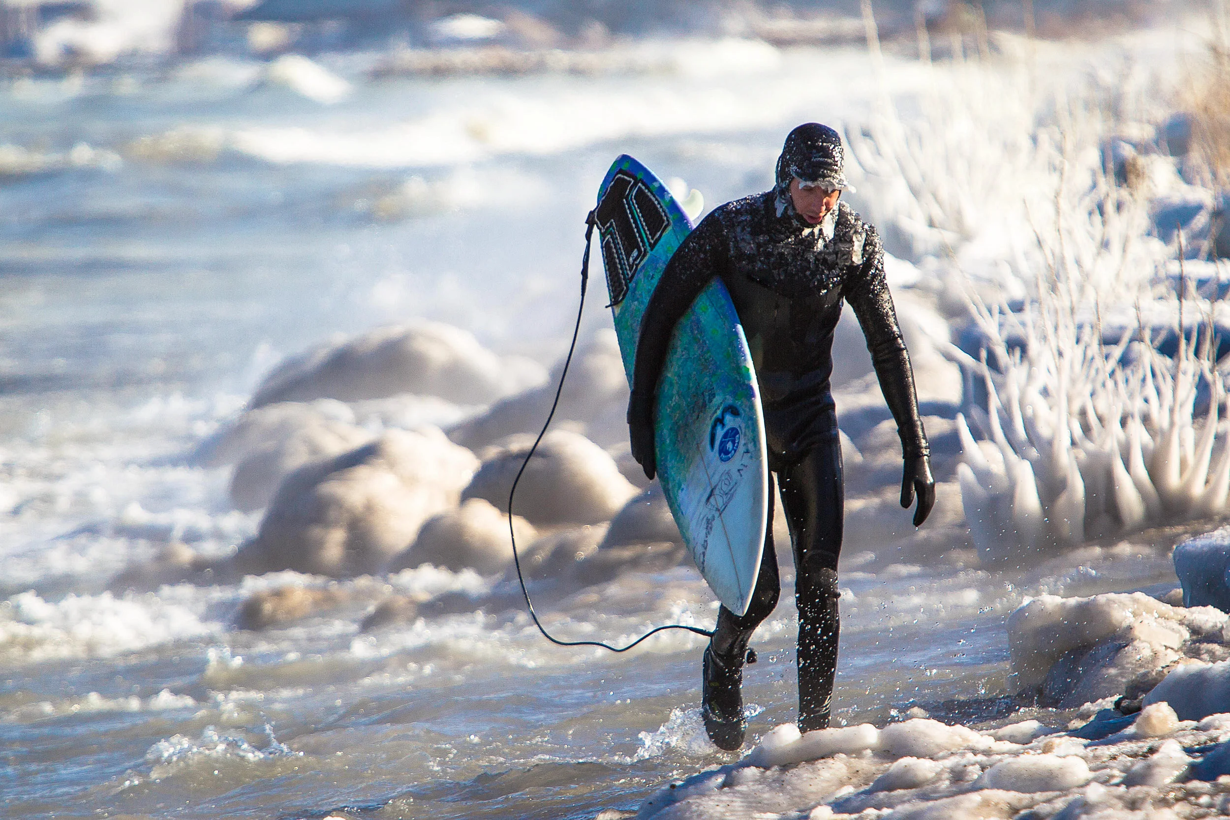 Surfer walking on the shore of lake michigan in the winter. Ice.&nbsp; 