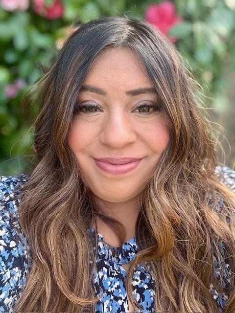 Stephanie smiling in front of flower bush