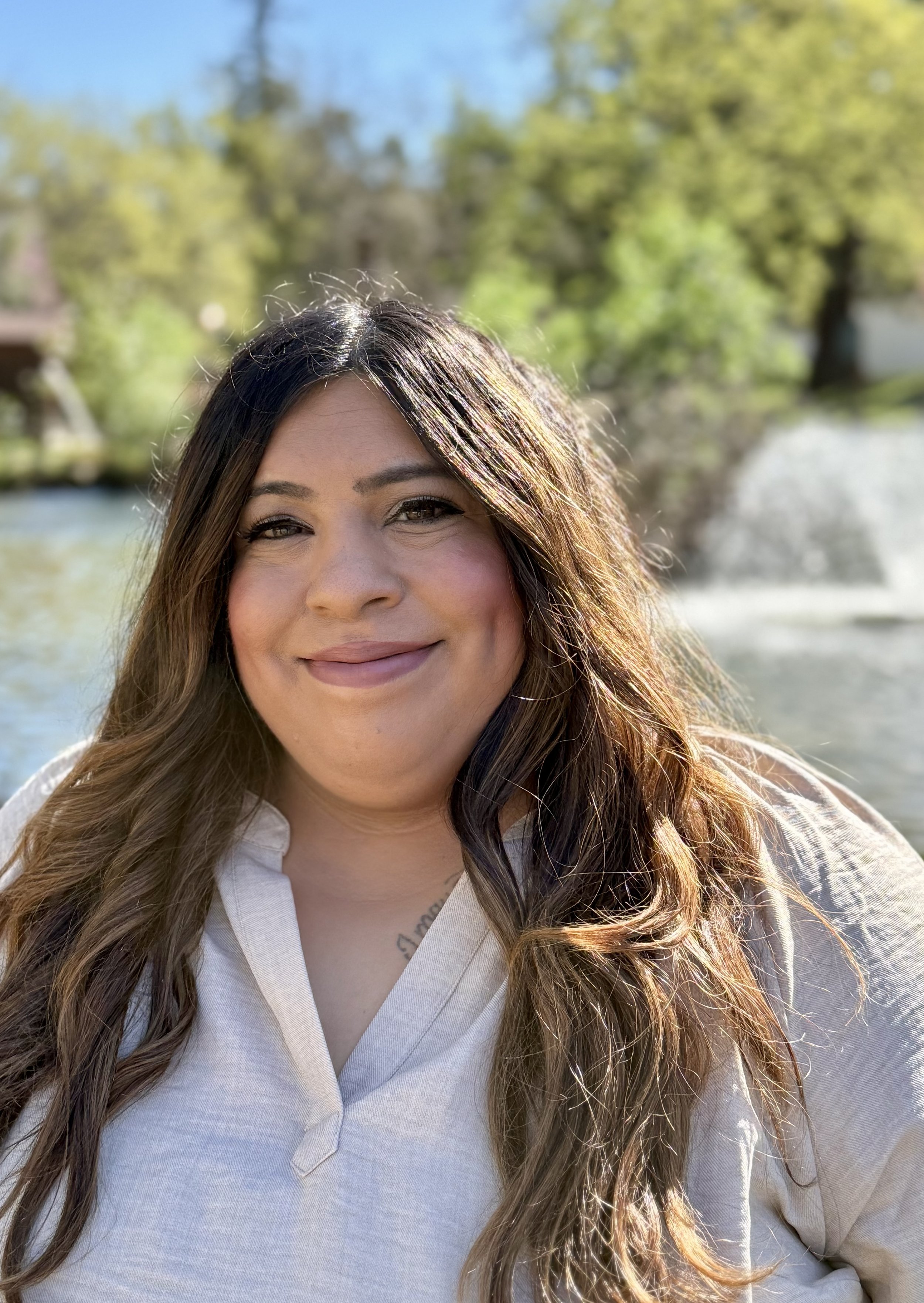 Stephanie smiling in front of a pond with a fountain