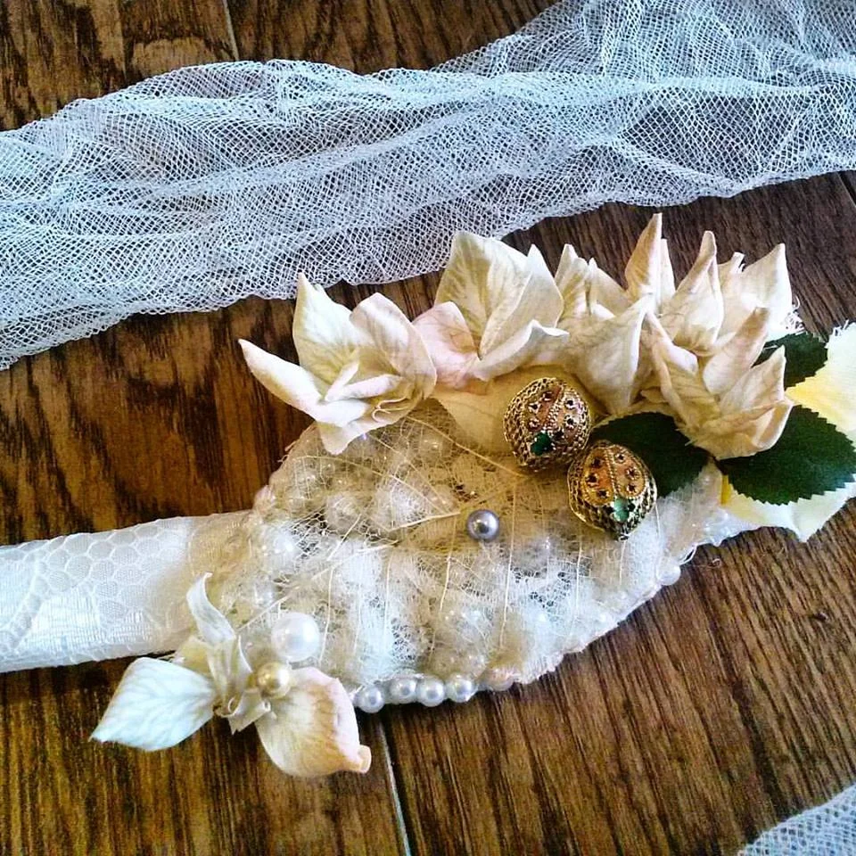 Amanda's Bridal Belt's motif was made from a dehydrated leaf that was hand sewn to antique lace and then sewn onto a bed of pearls. The two lady bugs are handmade Hungarian cloisonné beads who are 'feeding' off of a 'something blue' pearl! The belt was made from lace, hand sewn onto cream ribbon and attached to crinkled tulle at the side seams to tie into an elegant and rustic tie at her dress back. The effect was country and dramatic!