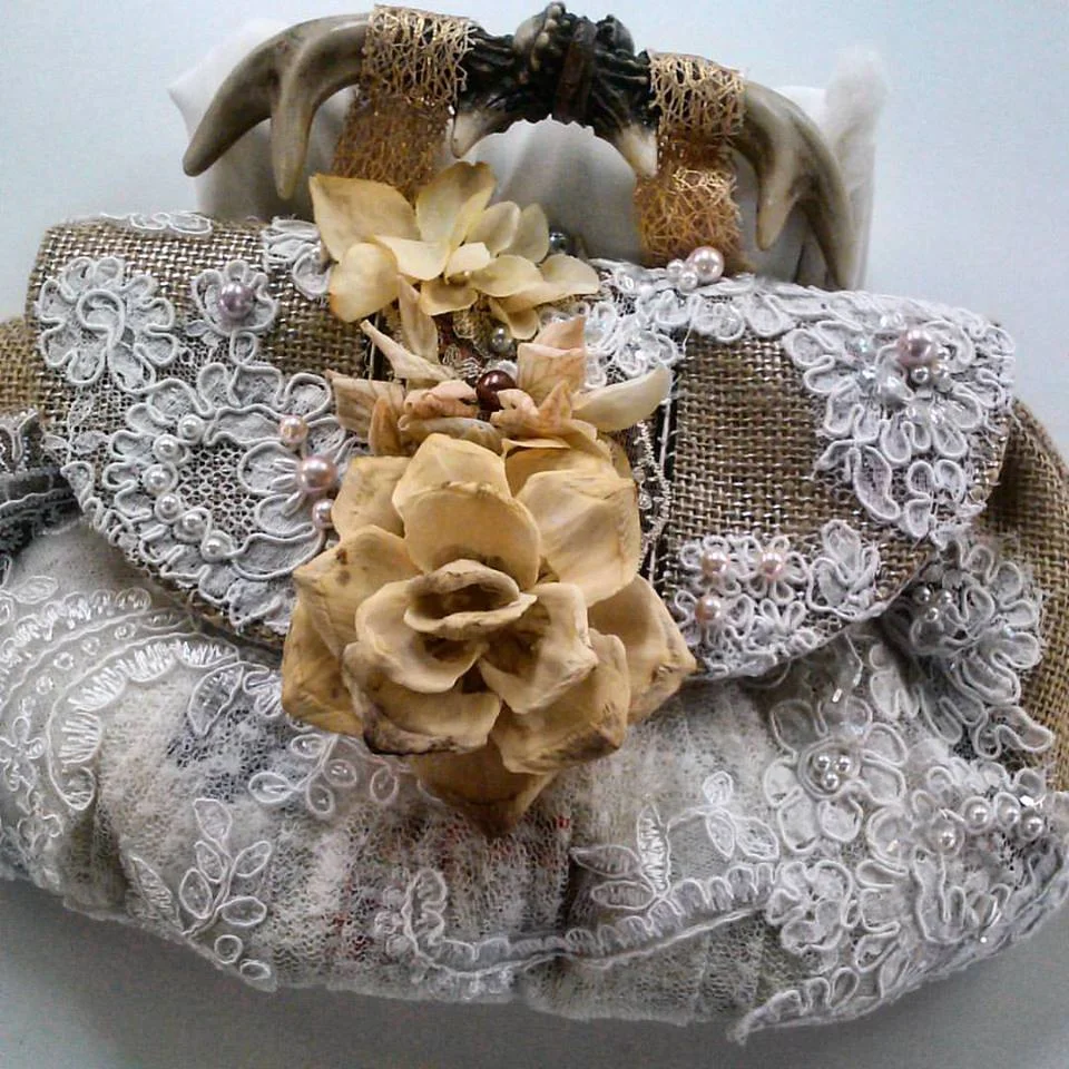 Amanda's Wedding Clutch was made from metallic burlap, vintage lace, blush pearls, strips of fabric from her first wedding dress, a wooden rose at the button and resin deer antler's as a handle!