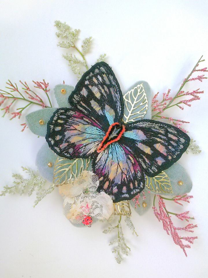To hide the elastic of the wreath's head band we made this velvet lamb's ear and butterfly comb. The butterfly was embroidered on top of feathers in lightened shades of yellow, blue and magenta.
