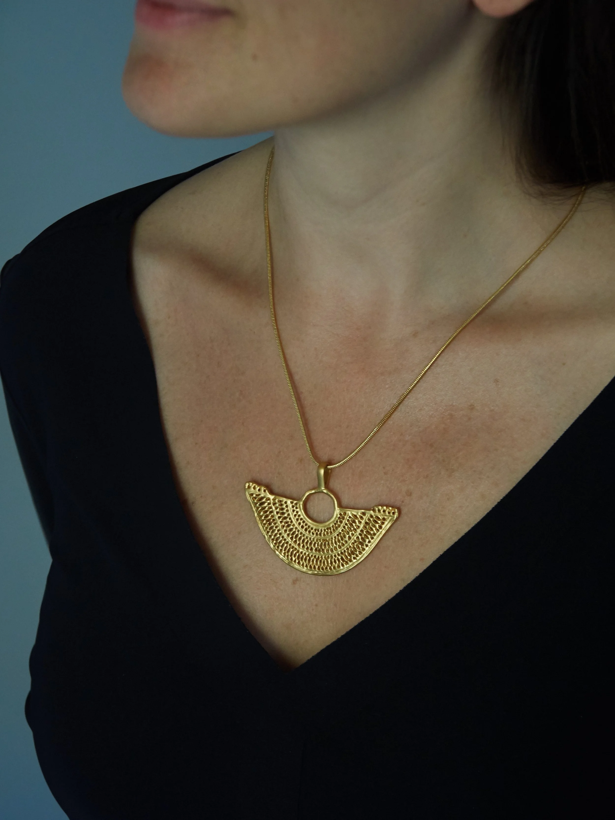 Gold-plated Zenú-inspired cast filigree pendant worn on a chain, based on the woven metalwork traditions of pre-Columbian Colombia.
