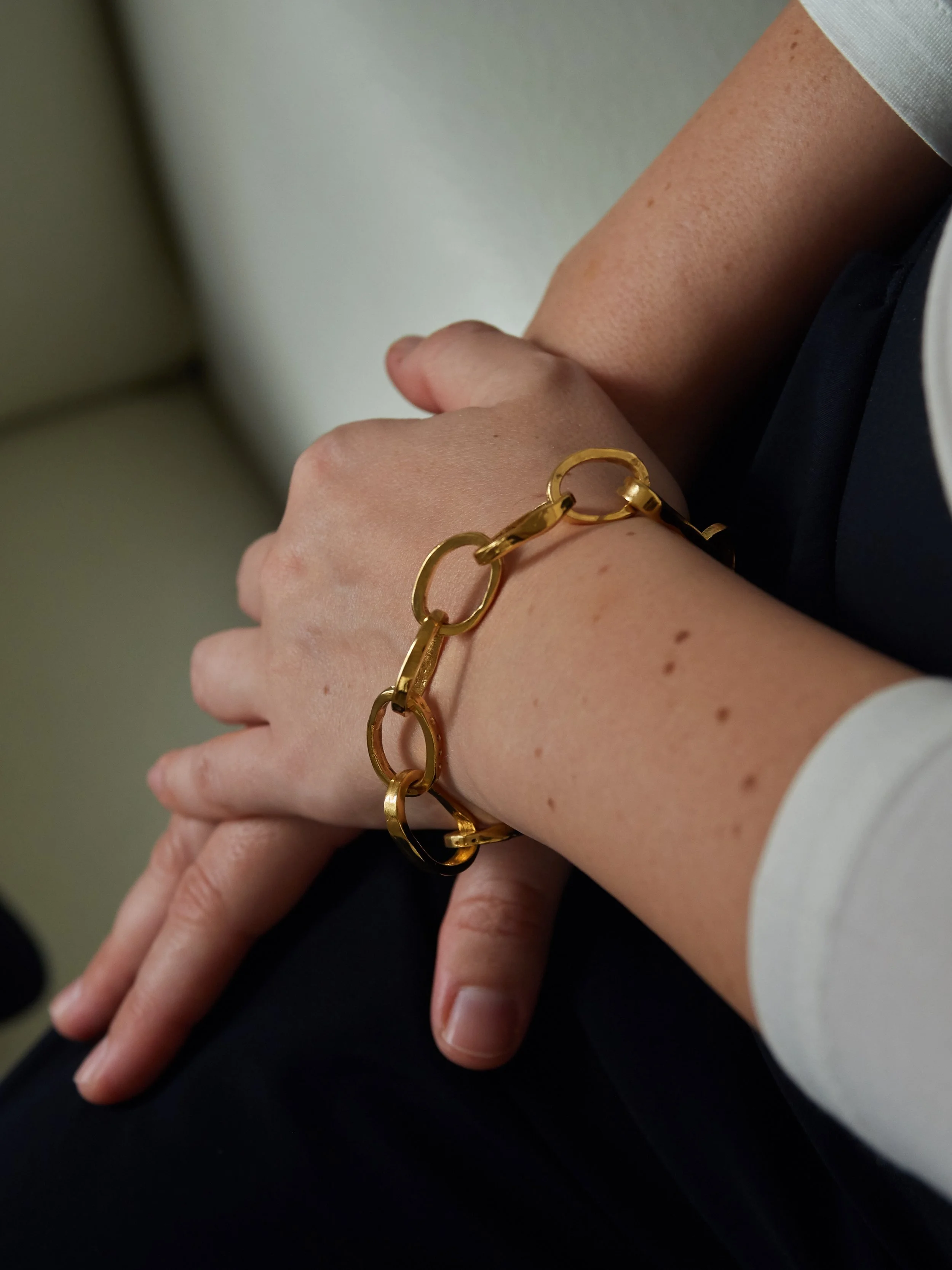 CHAINETTE gold-plated bronze bracelet by Elisabeth Riveiro, featuring irregular interlocking oval links, worn on the wrist.