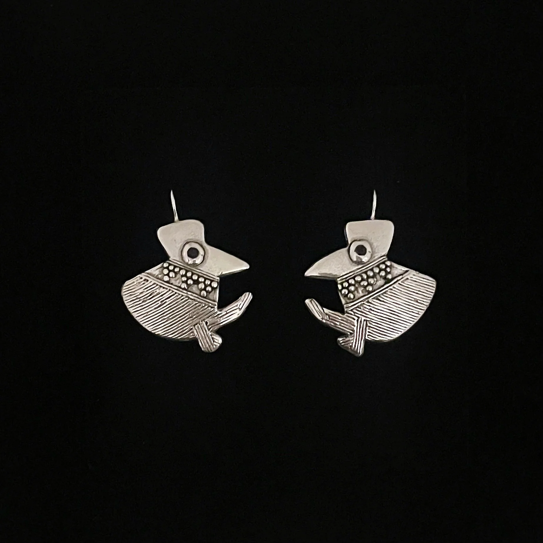 Piano bird earrings by Elisabeth Riveiro in silver-plated bronze, featuring two stylised birds with finely engraved plumage, decorative relief details and dark enamel eyes.