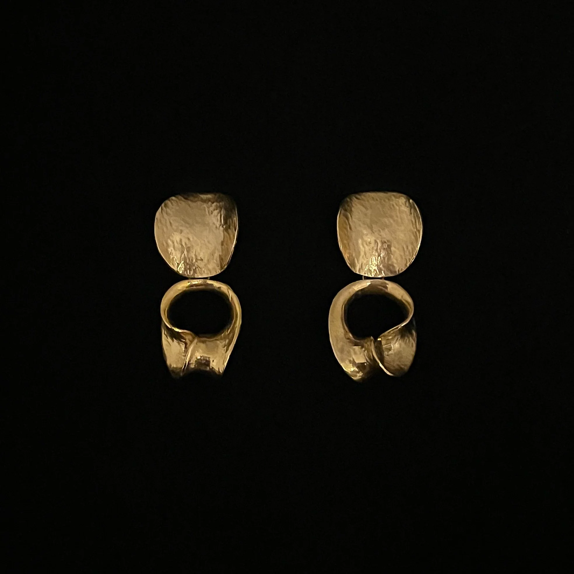 Pair of Ovaljazz Small gold-plated bronze earrings by Elisabeth Riveiro, with textured oval studs and sculptural openwork pendants, photographed against a black background.