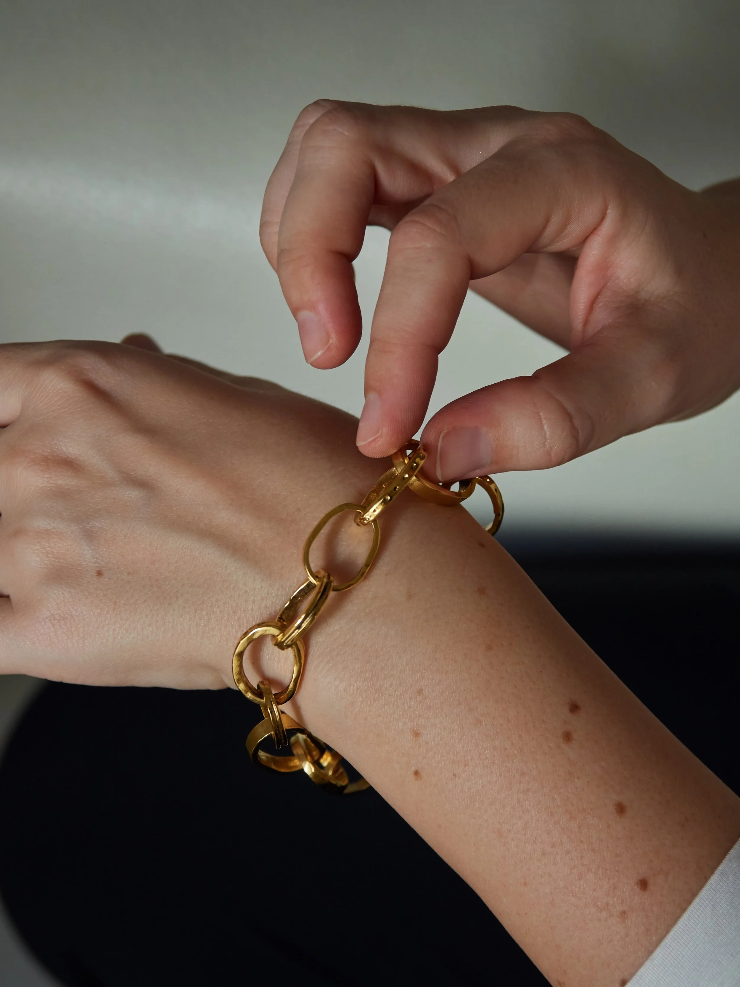 Detail of the CHAINETTE gold-plated bronze bracelet by Elisabeth Riveiro, featuring handcrafted oval links and an adjustable fastening.