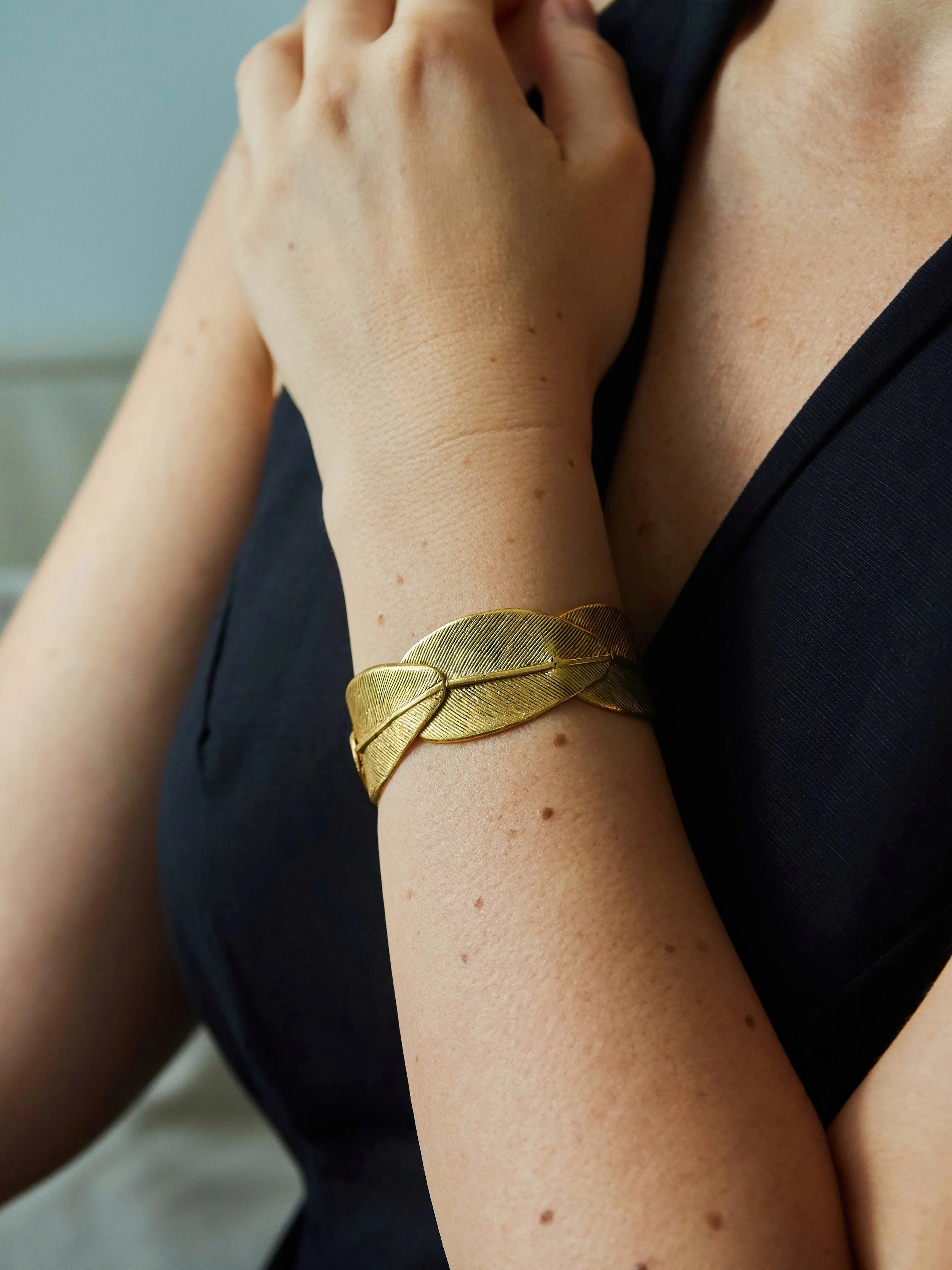 Elisabeth Riveiro Olympe gold-plated bronze leaf cuff bracelet worn with a black outfit.