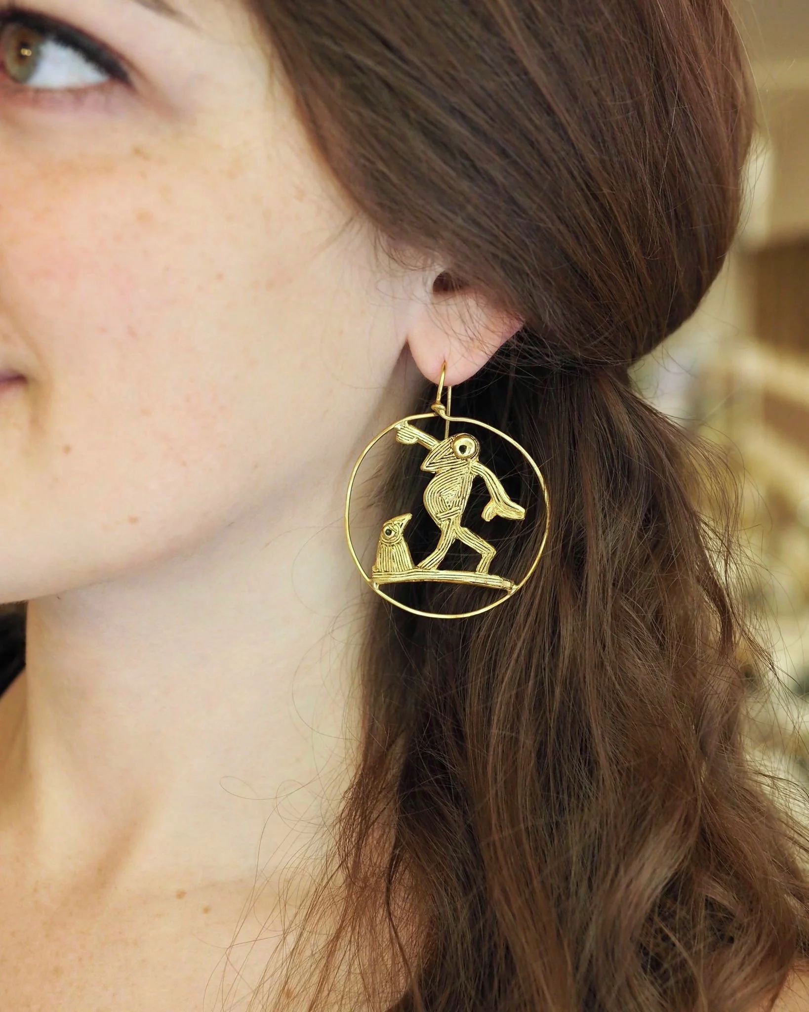Farandole gold-plated bronze earrings by Elisabeth Riveiro, worn view highlighting dynamic circular bird composition.