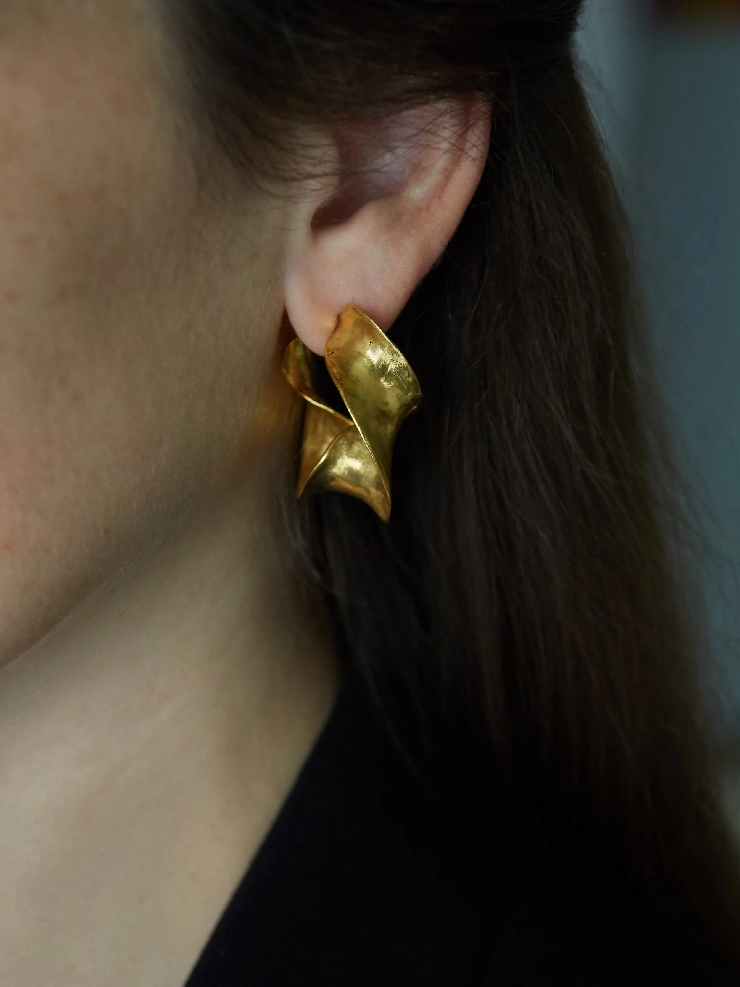 Elisabeth Riveiro Jazz Multi gold-plated bronze hoop earrings, worn to reveal their sculptural overlapping curves, softly textured surfaces and interplay of light and shadow.