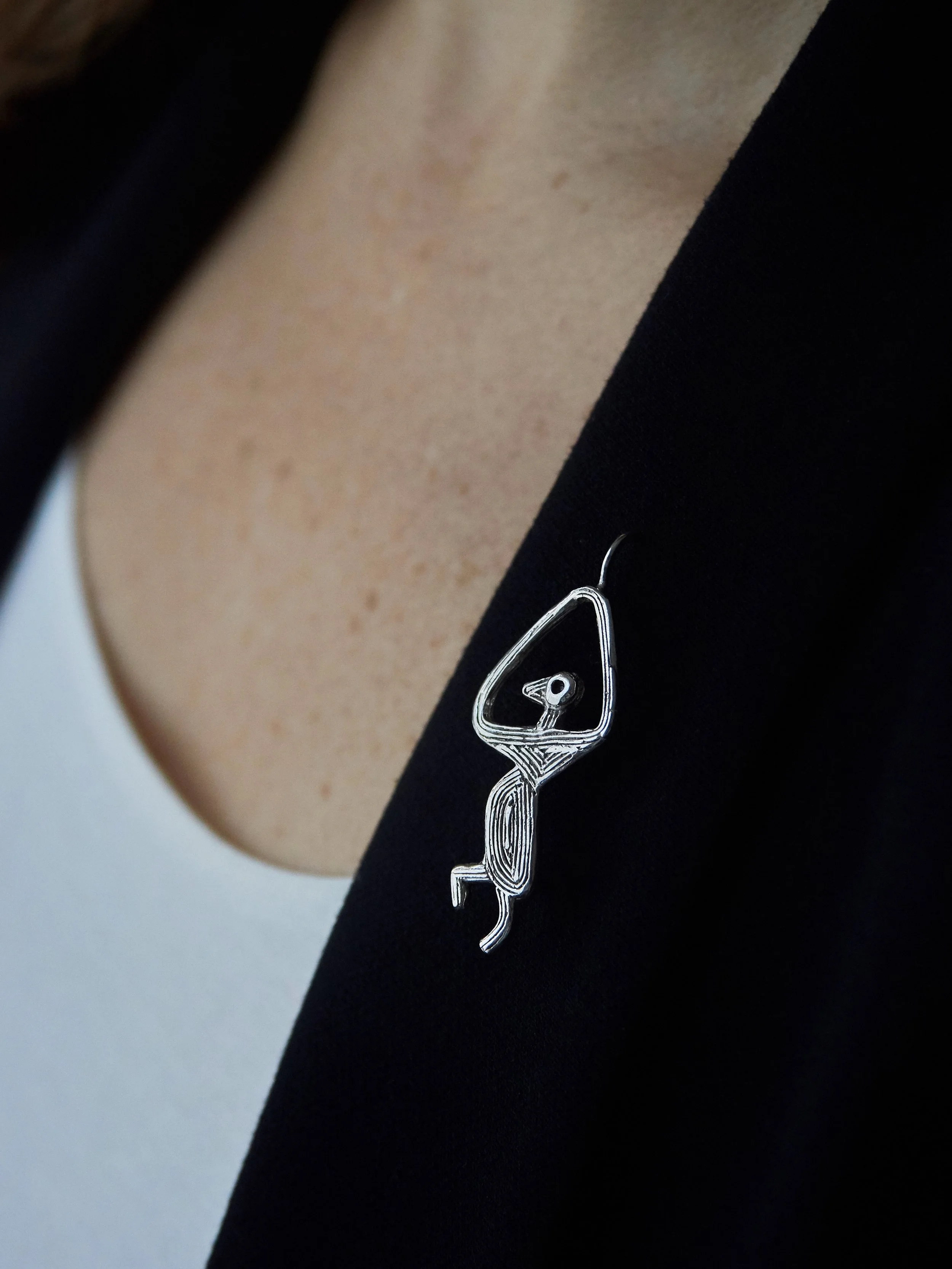 Isadora bird fibula brooch in silver-plated bronze by Elisabeth Riveiro, handcrafted using lost-wax casting, worn on a dark blazer – AMBART Palma de Mallorca.