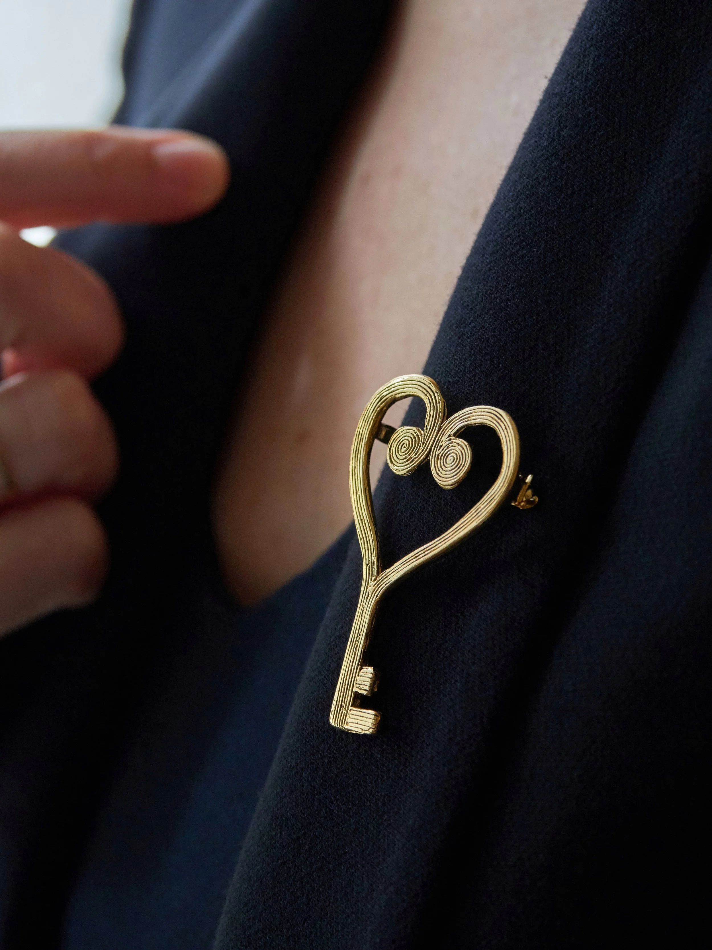 Gold-plated bronze Heart Key brooch by Elisabeth Riveiro, handcrafted in Paris and worn on a navy blazer
