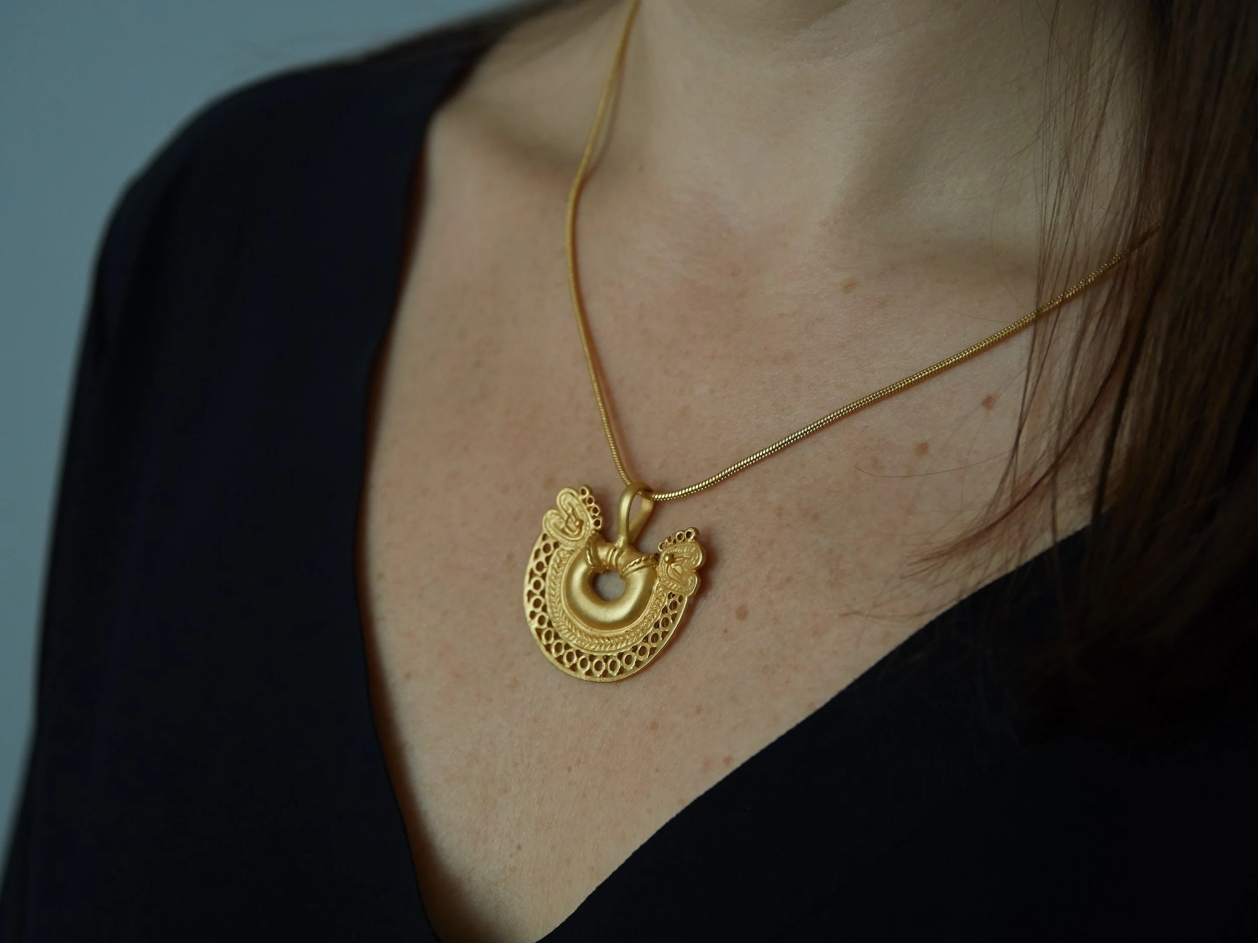 Gold-plated Tairona-inspired double-headed serpent pendant worn on a chain, based on pre-Columbian Colombian goldwork.
