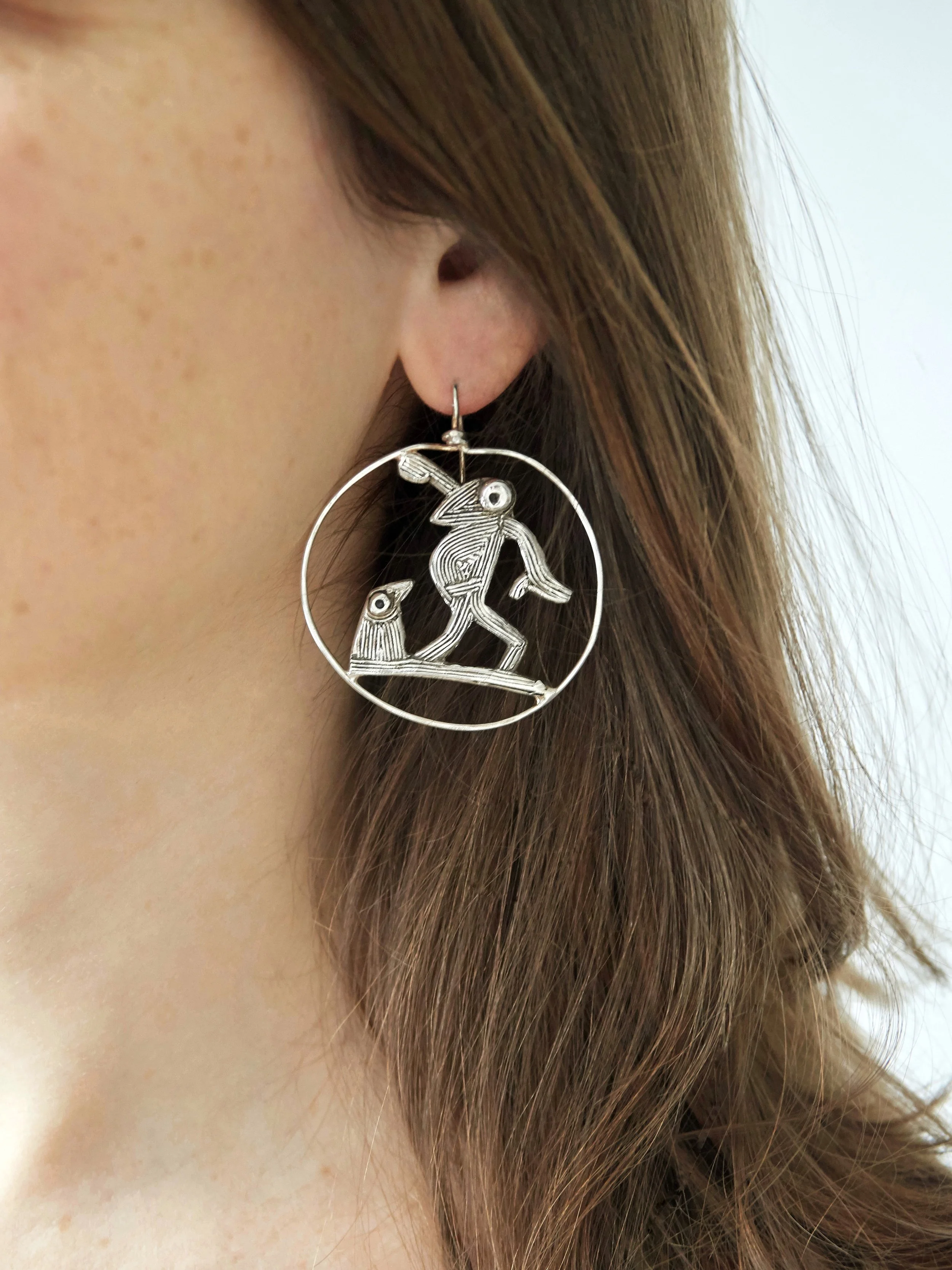 Farandole dancing bird earrings by Elisabeth Riveiro in silver-plated bronze, worn view showing circular movement-inspired design.