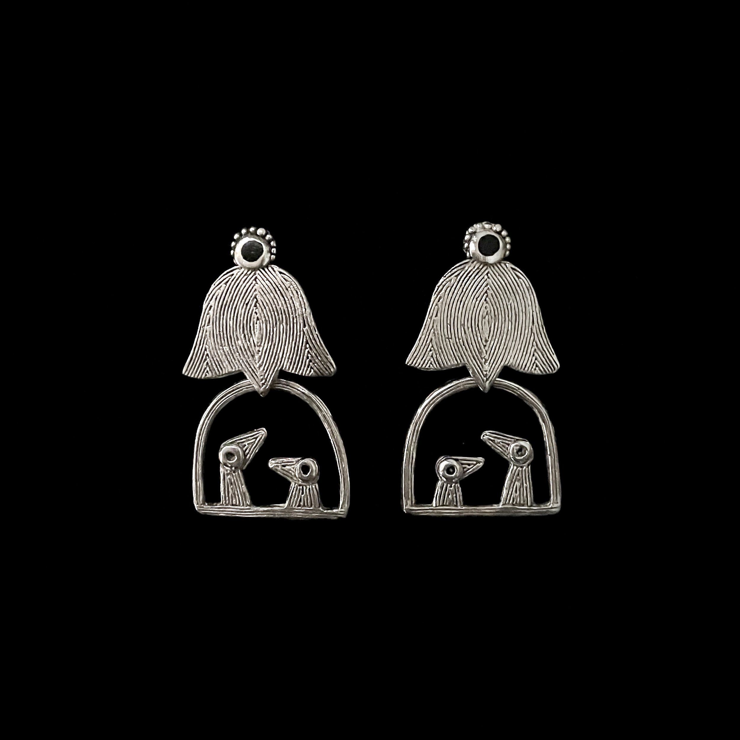 Long “Père et Fils” bird earrings by Elisabeth Riveiro in silver-plated bronze, with two stylised birds sheltered under a lotus-shaped element, handcrafted in Paris using traditional lost-wax casting.