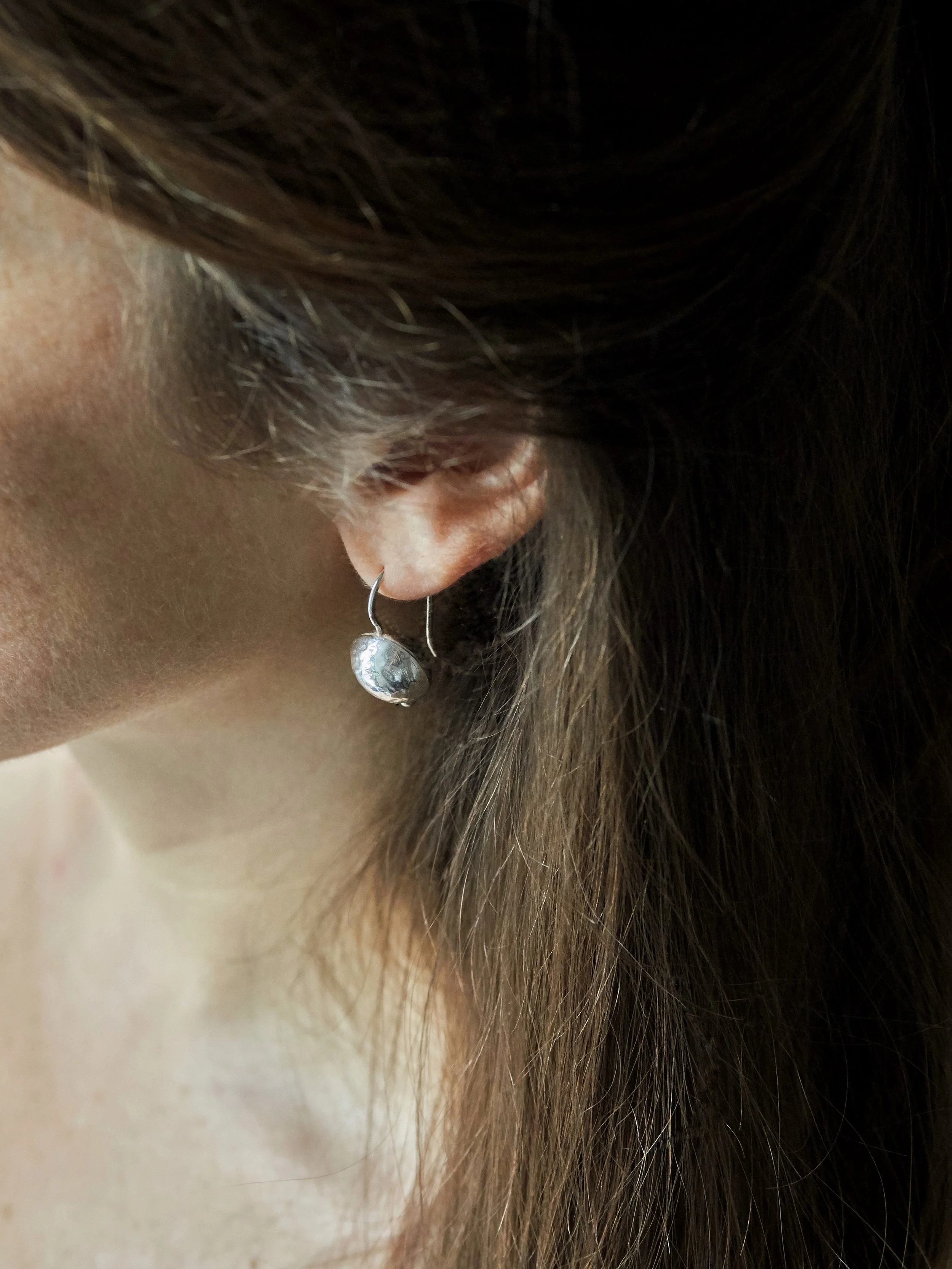 Petite Sphère earrings by Elisabeth Riveiro in silver-plated bronze, small sculptural sphere earrings worn close-up.