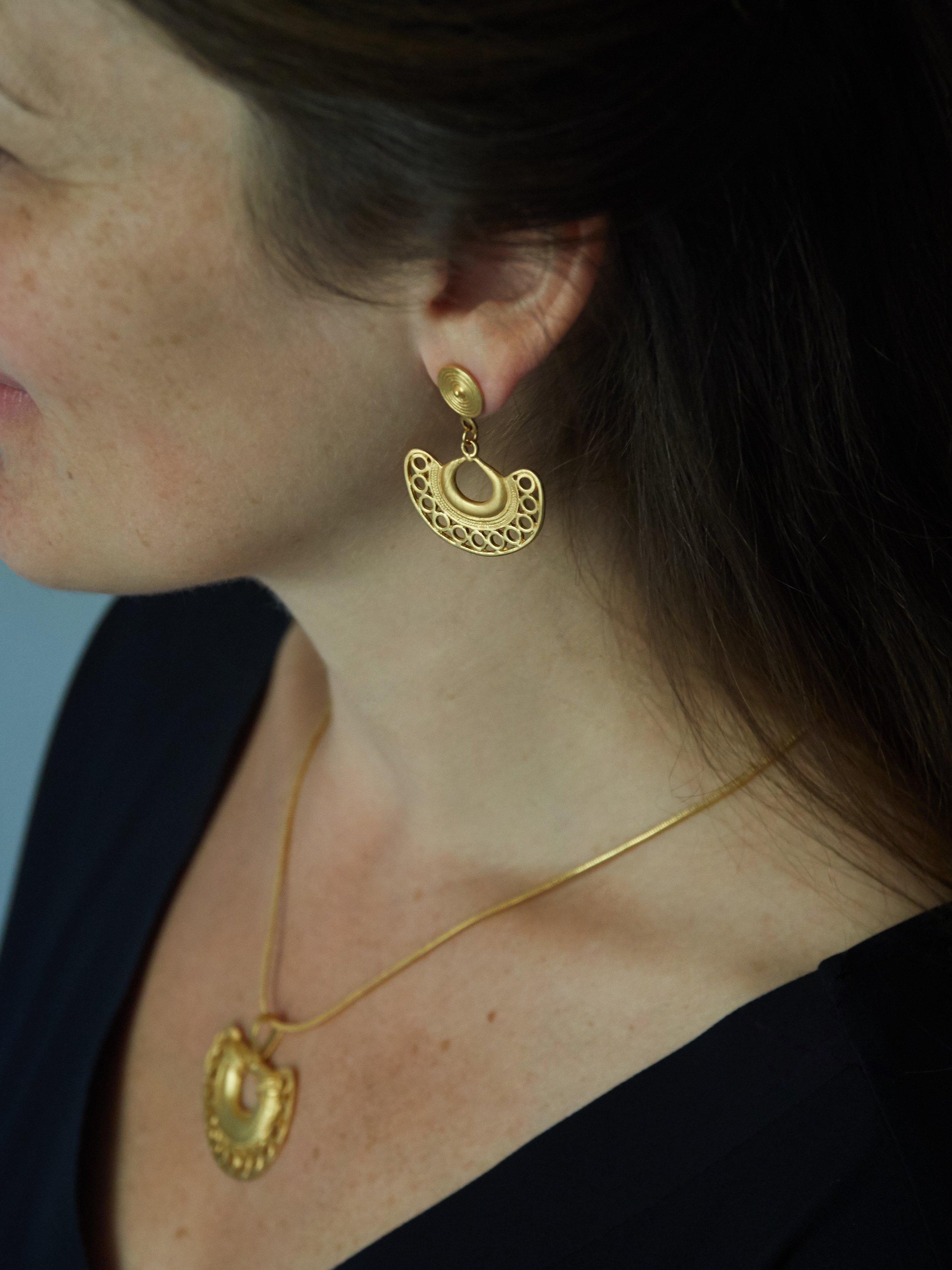 Tairona-inspired semilunar earrings worn with a matching gold-plated pendant from the Galeria Eldorado collection