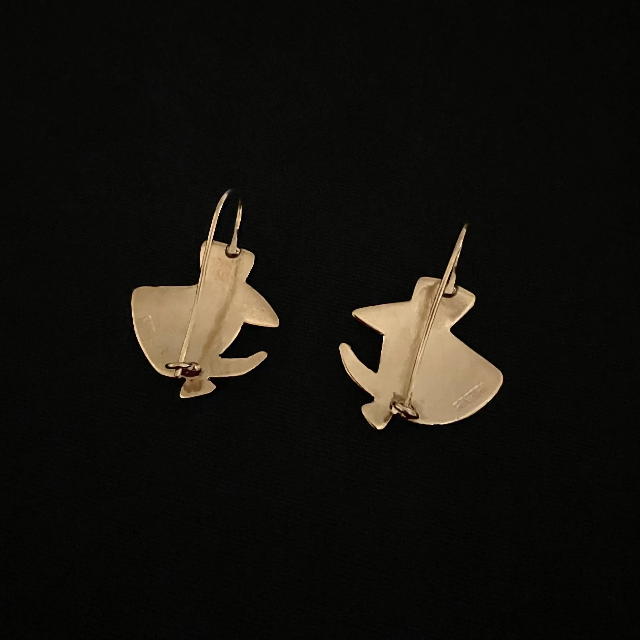 Back view of the Piano bird earrings by Elisabeth Riveiro in gold-plated bronze, showing their smooth reverse and curved ear hooks, photographed against a black background.